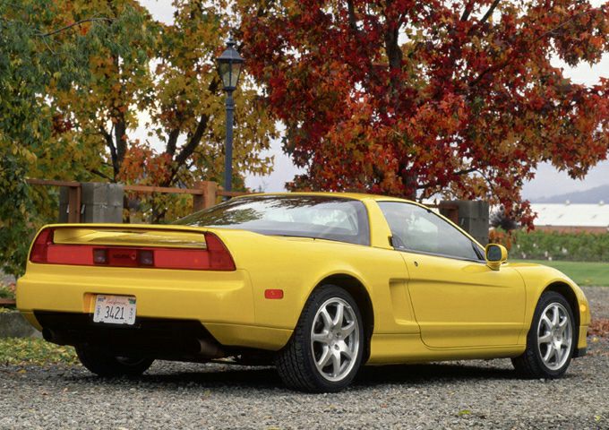 Yellow sports coupe with rear spoiler and alloy wheels parked outdoors.