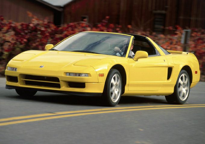 Front three-quarter view of a yellow sports coupe with pop-up headlights