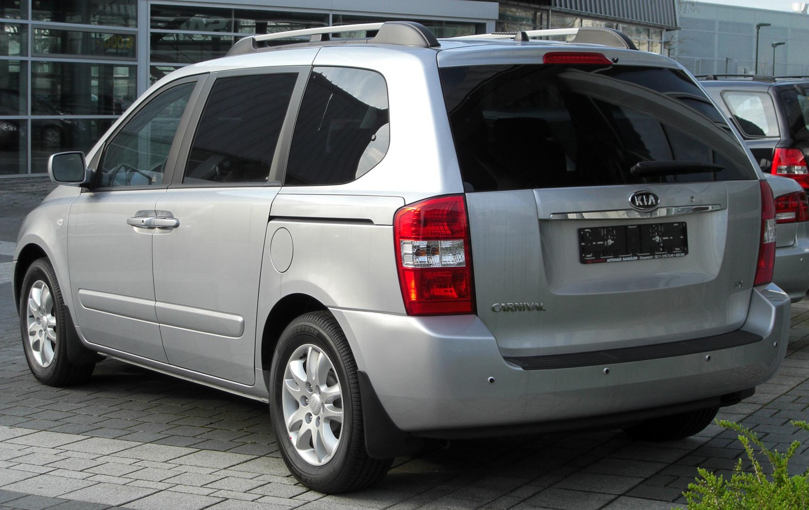 Silver minivan rear view with roof rails and tinted rear windows