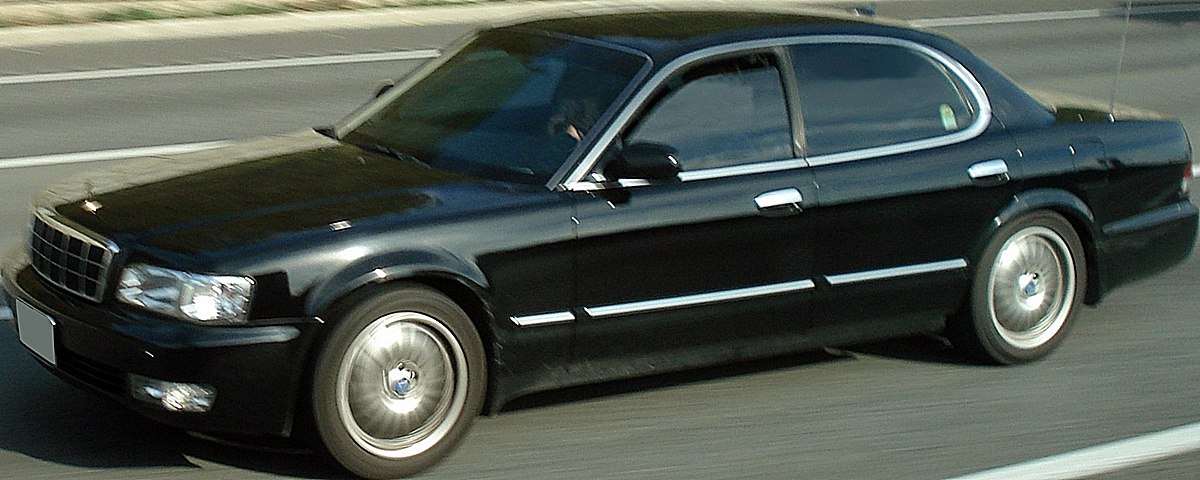 Black sedan with chrome trim and alloy wheels on road