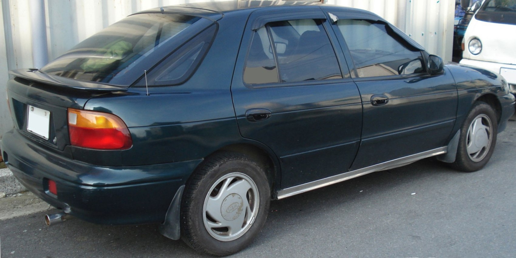 Rear-side view of a 1990s hatchback with spoiler and four doors