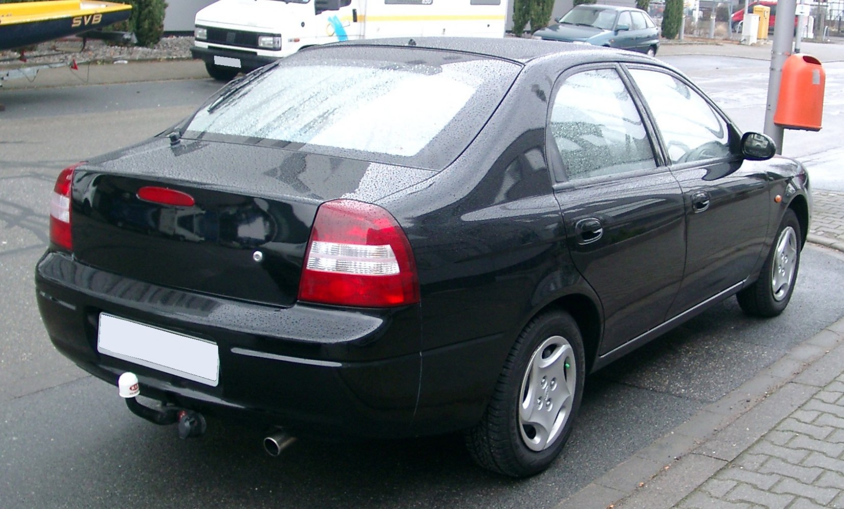 Rear view of black four-door sedan with tail lights and tow hitch