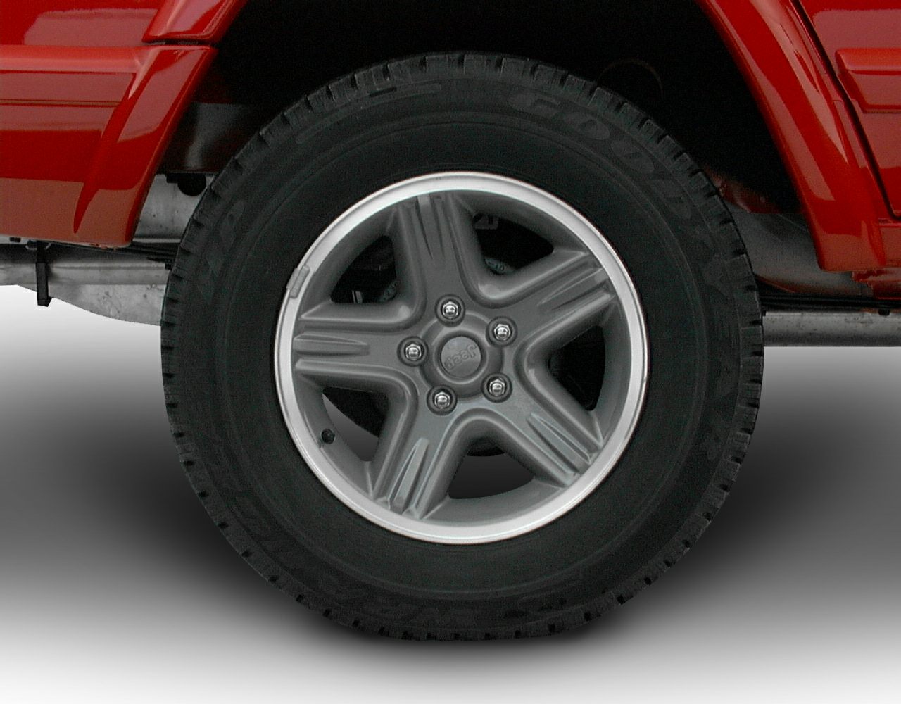 Close-up of classic five-spoke alloy wheel and tire on rugged vehicle.