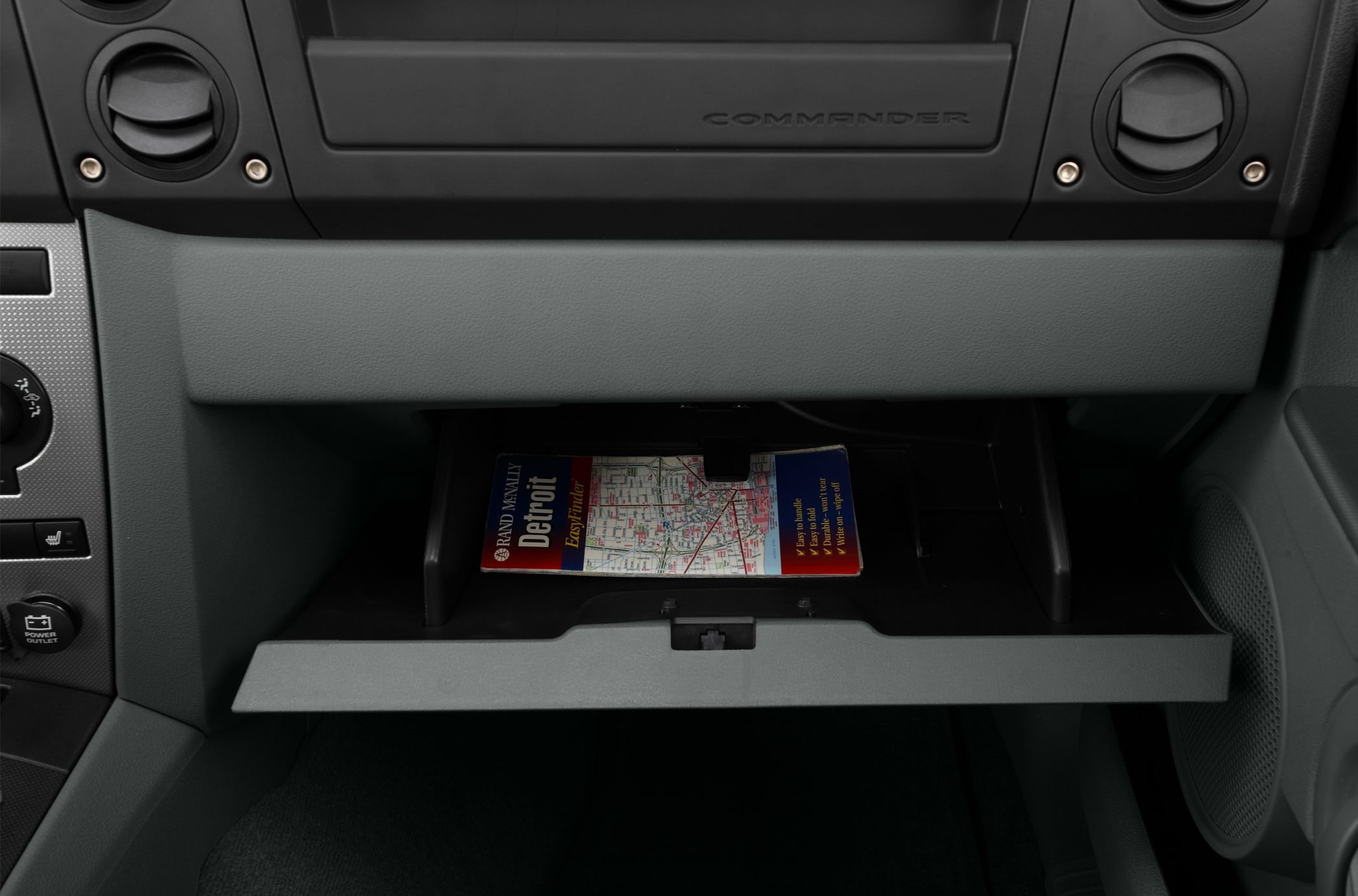 Open glove box with map inside and dashboard vents