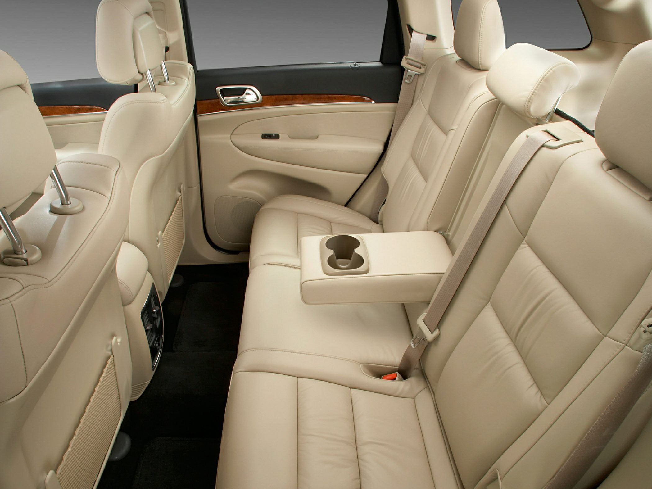Beige leather rear seats with fold-down armrest and cup holders.
