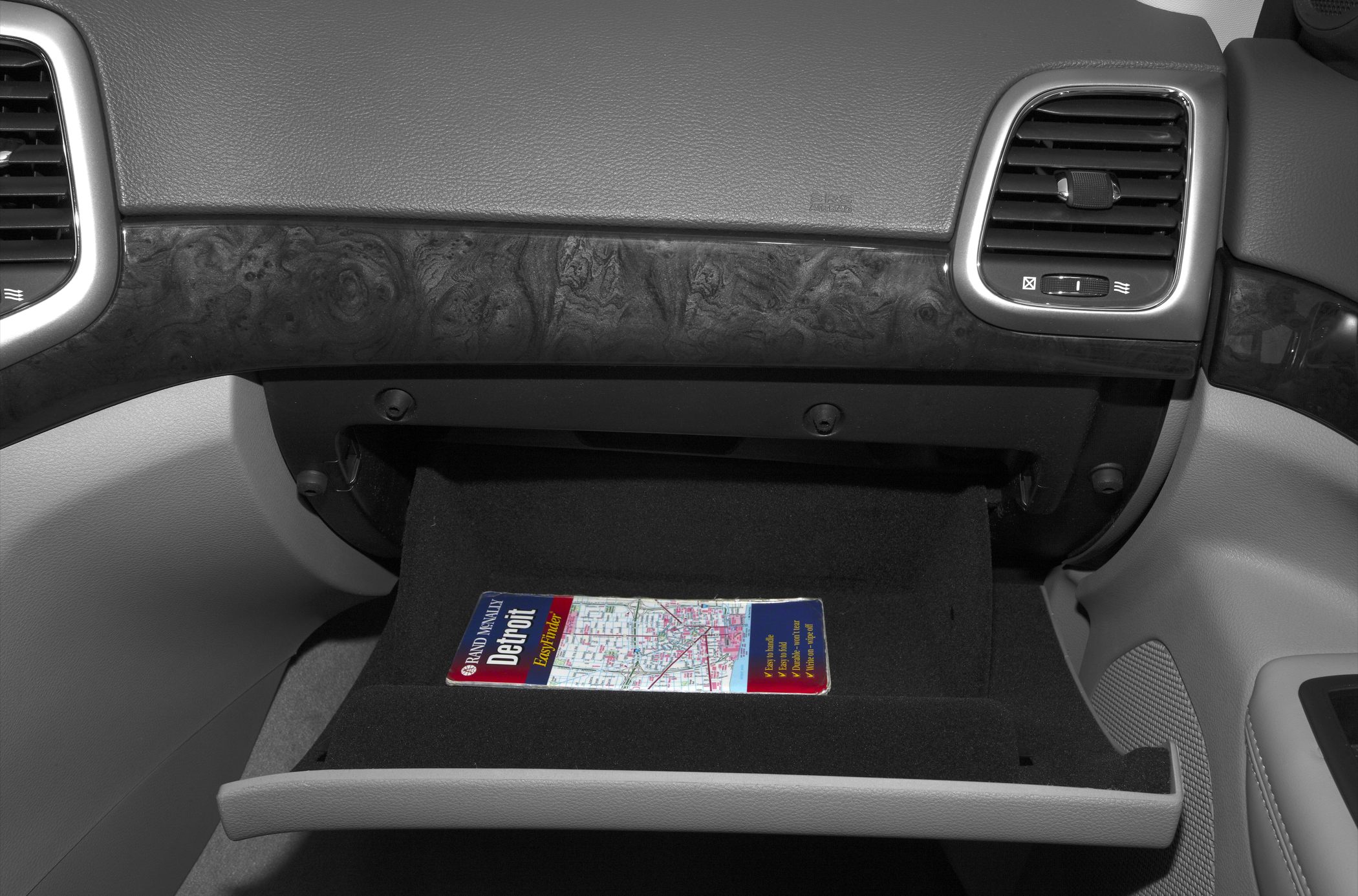 Open glove compartment with wood trim dashboard and air vents