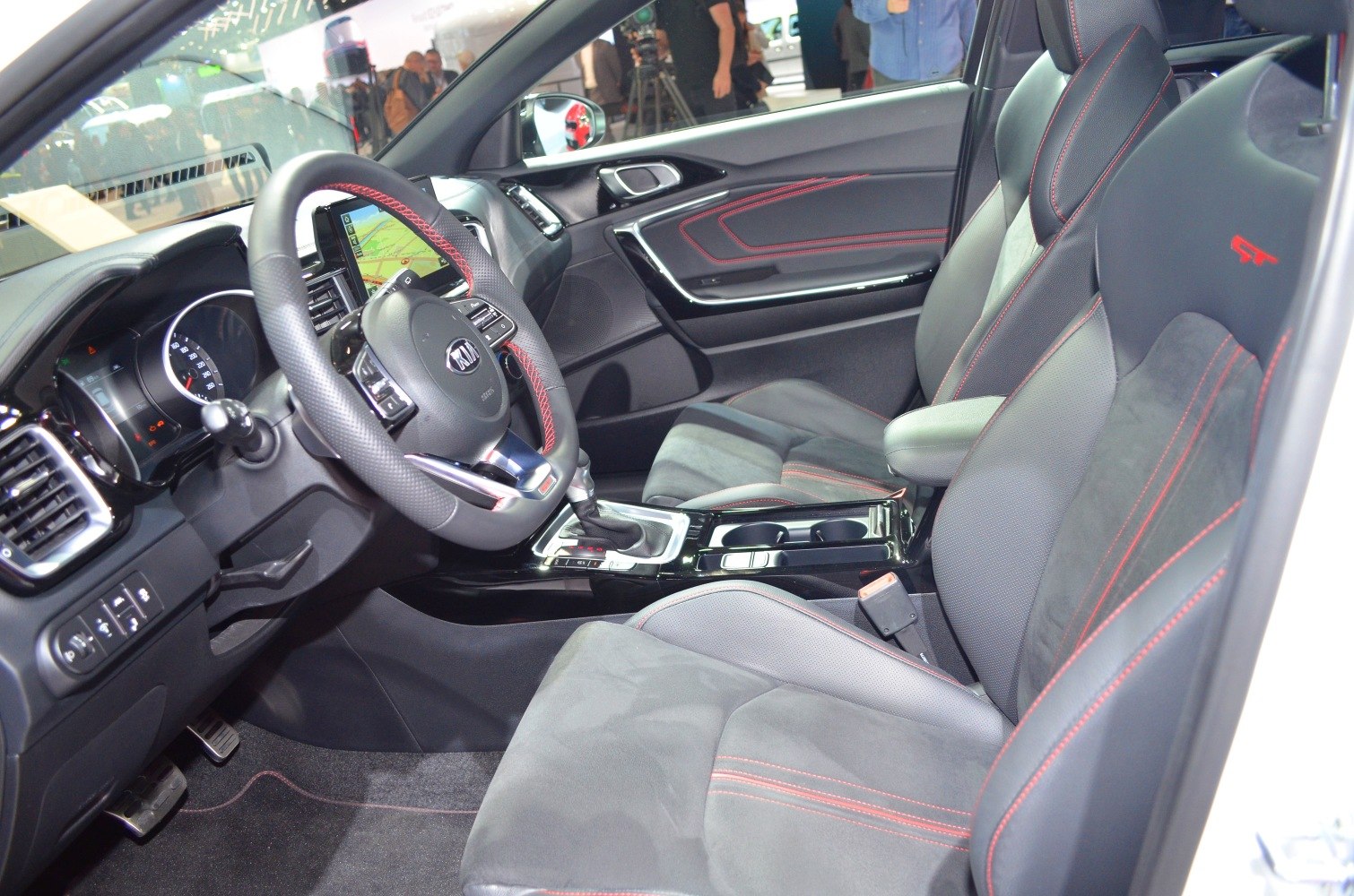 Sporty car interior with red stitched seats and infotainment system.