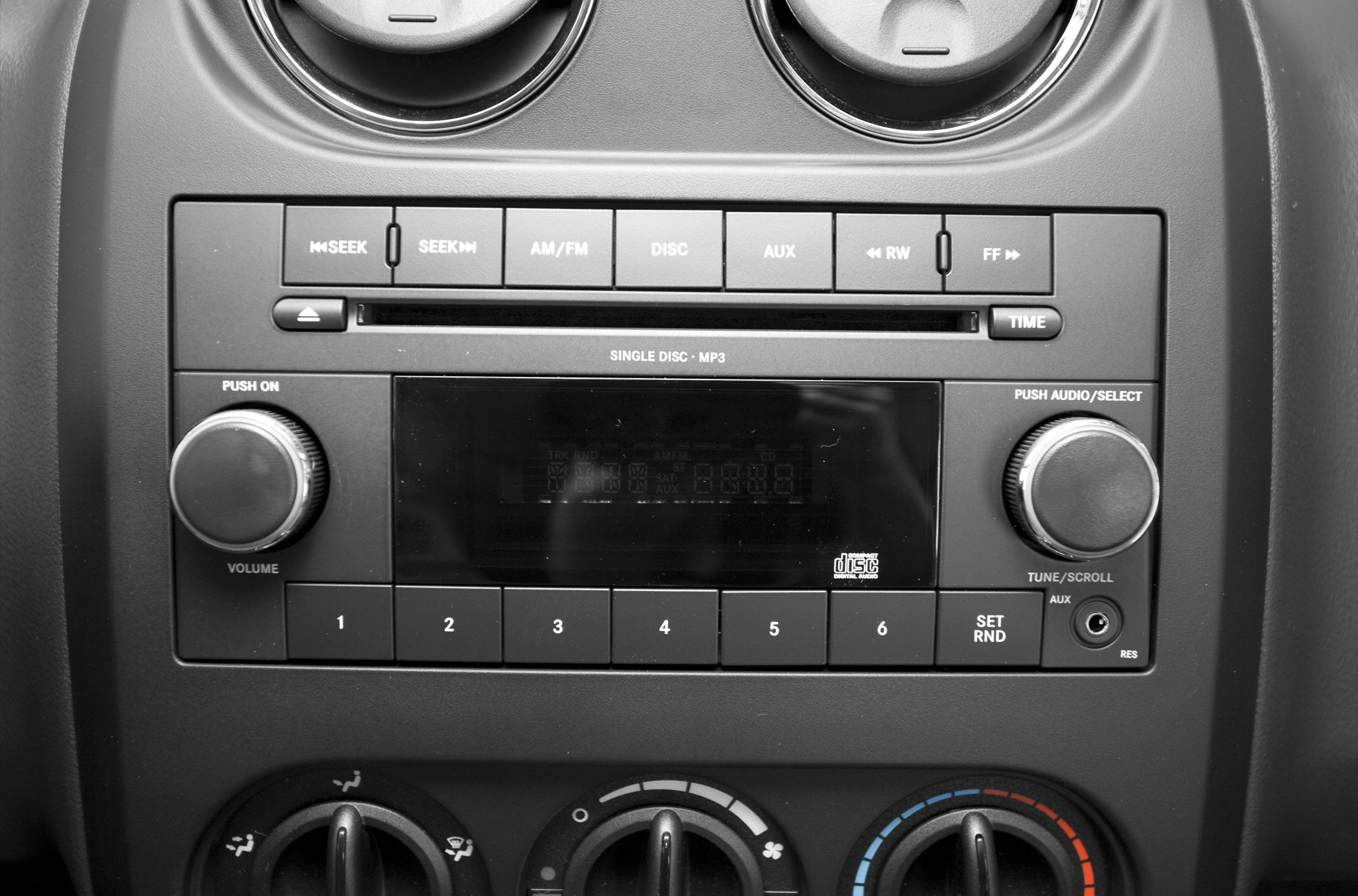 Car stereo and manual climate control panel with MP3 disc player and tuning knobs.