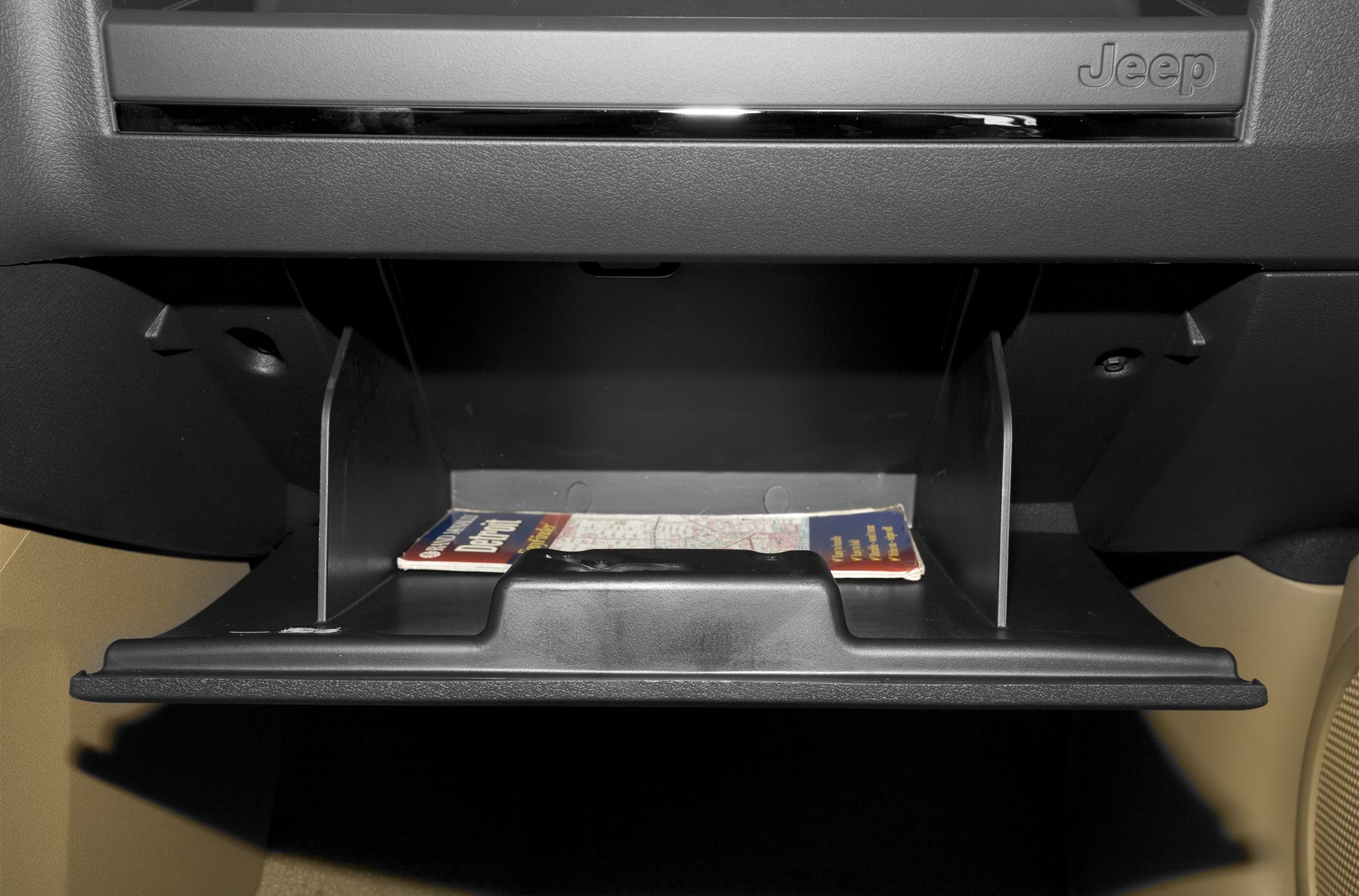 Open glove compartment with map inside and Jeep logo above