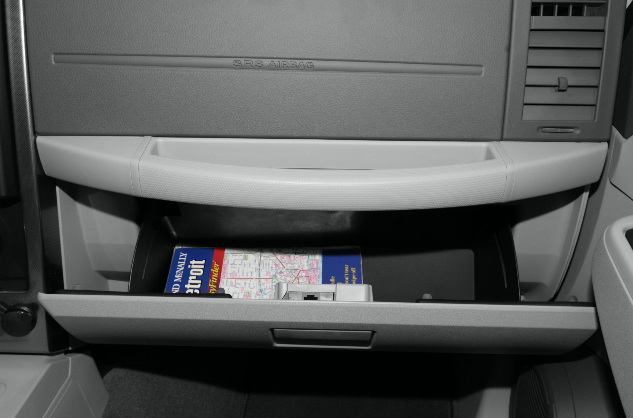 Dashboard glove compartment with open storage space and map inside