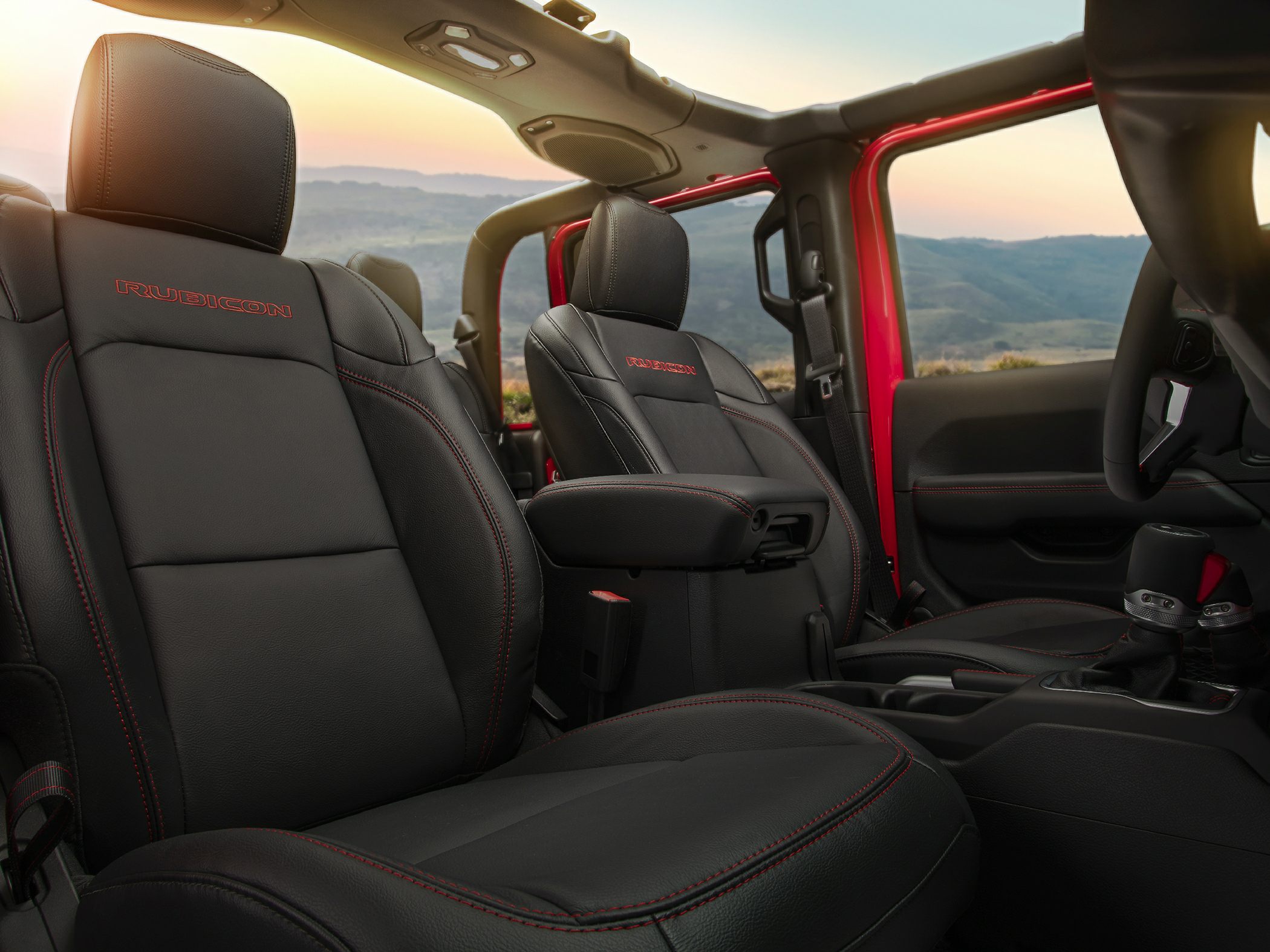 Close-up of black leather seats with red stitching and center console.