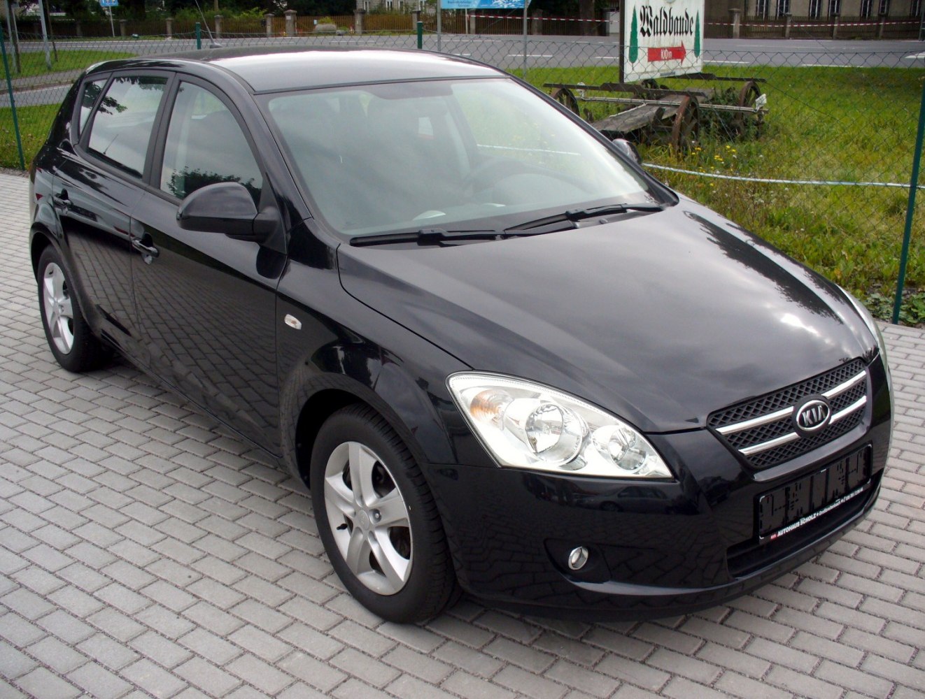 Front side view of black hatchback showing headlights and alloy wheels