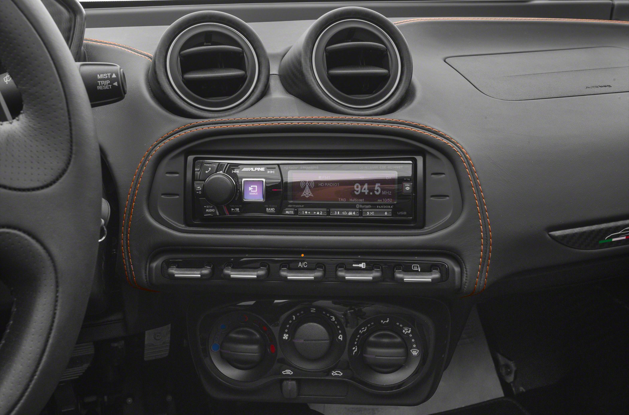 Alpine stereo and climate control knobs with orange stitched dashboard