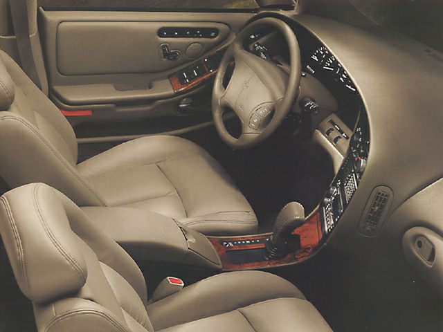 Beige leather seats and woodgrain trim inside a classic luxury car interior.