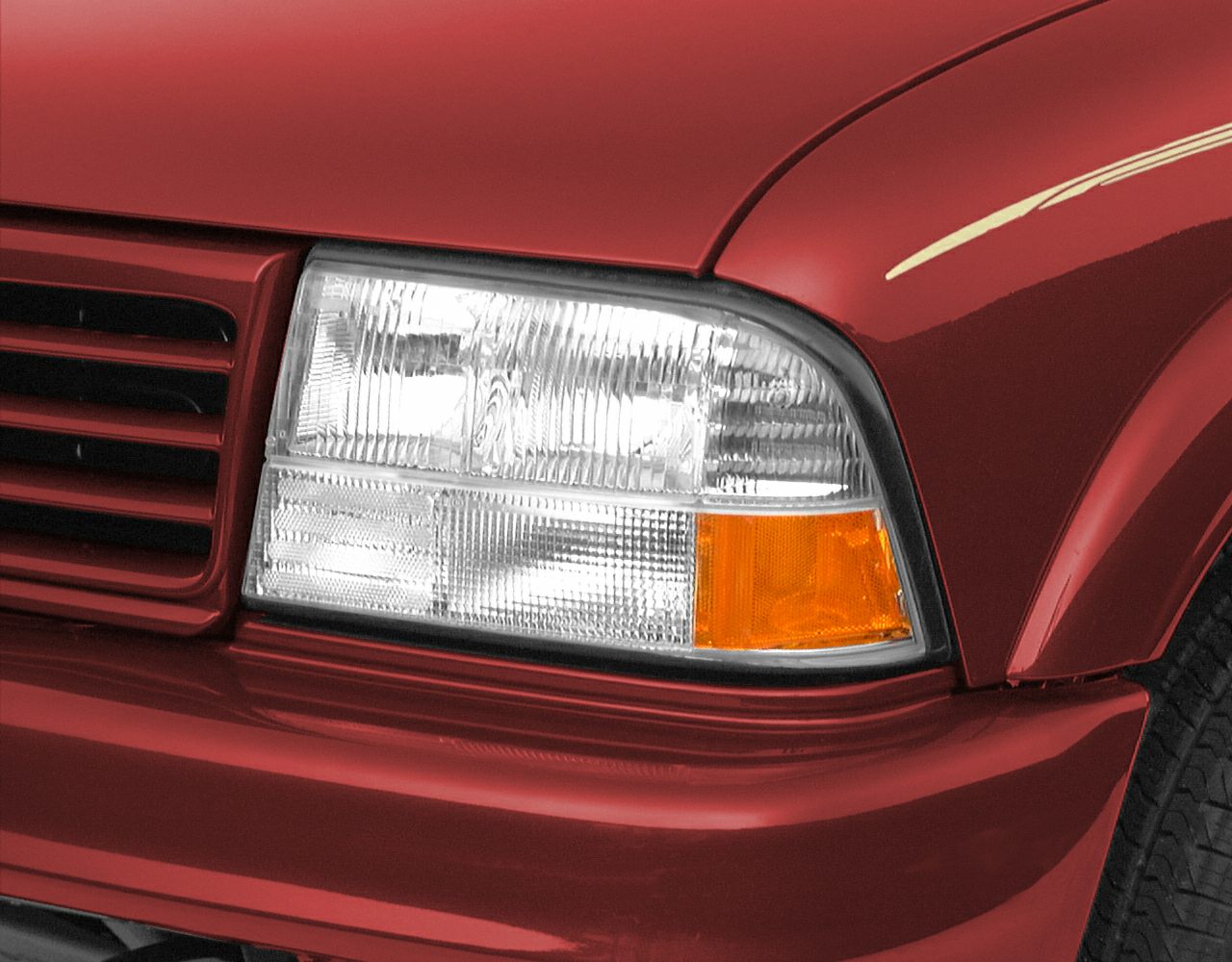 Close-up of clear multi-section headlight and red front fender with amber indicator