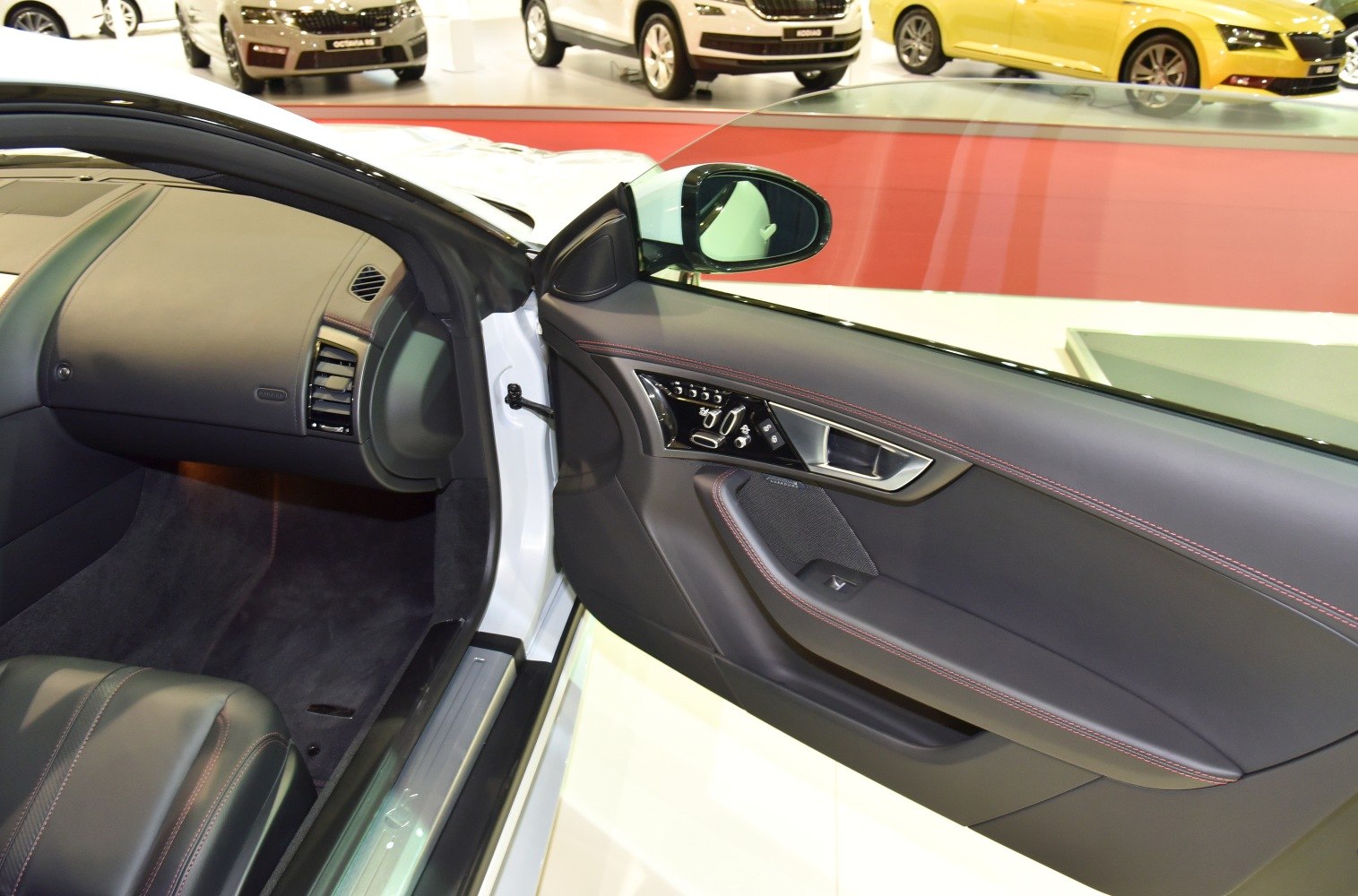 Luxury black leather door panel with red stitching and control buttons.
