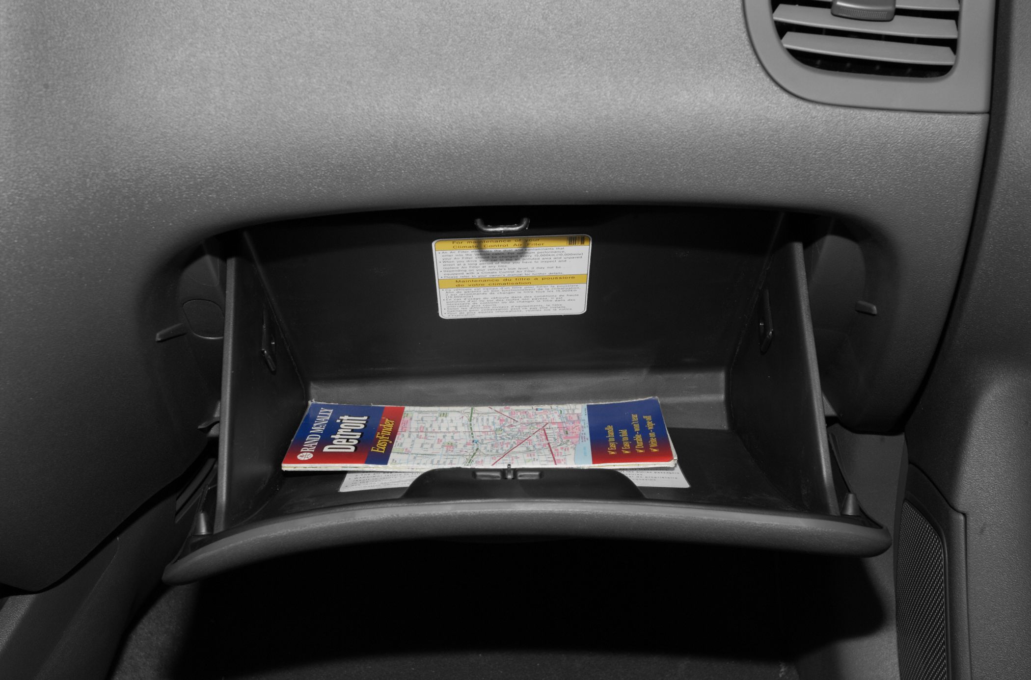 Open glove box with visible storage compartment and manual