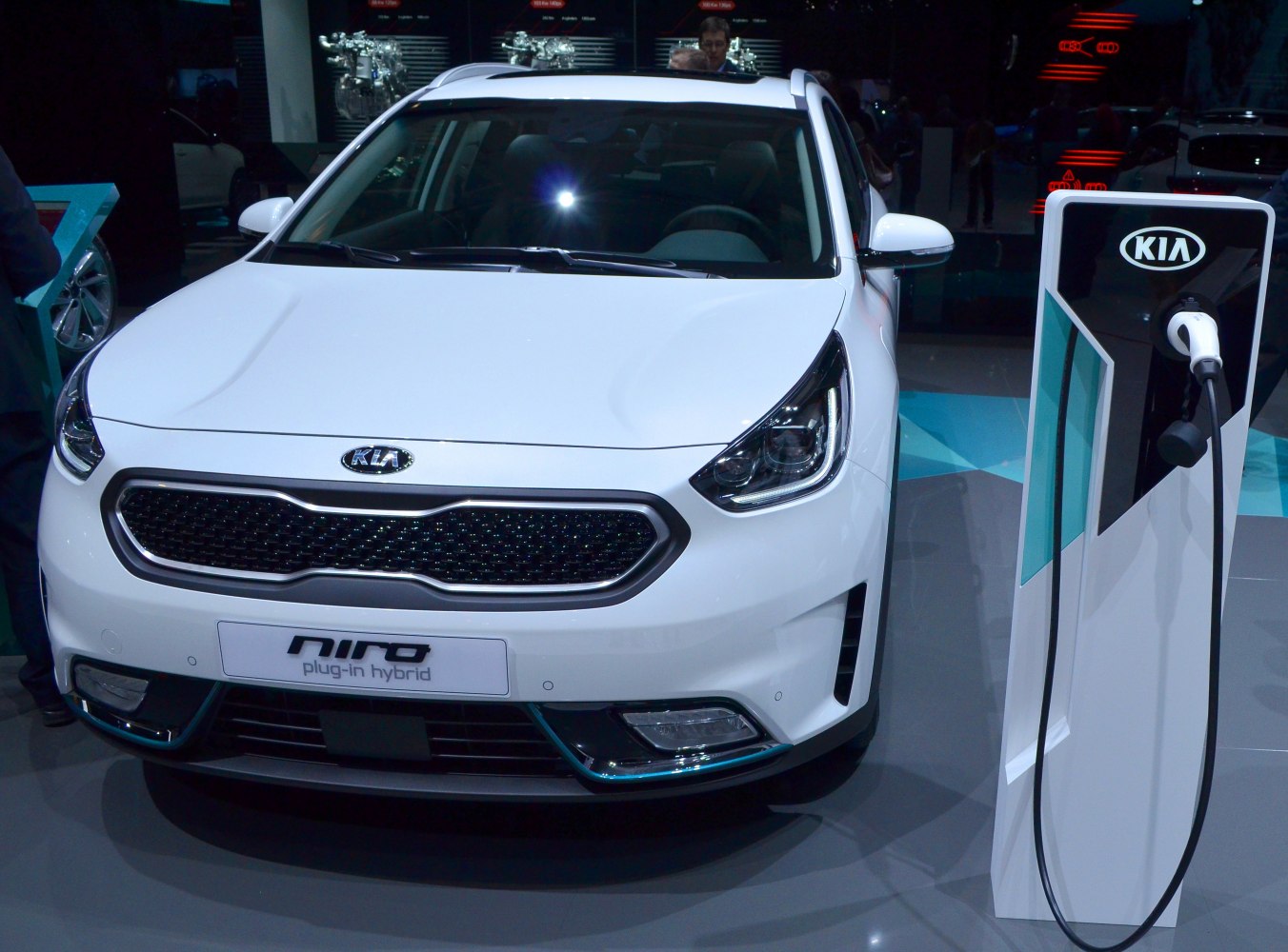 Front view of a white plug-in hybrid vehicle with charging station.