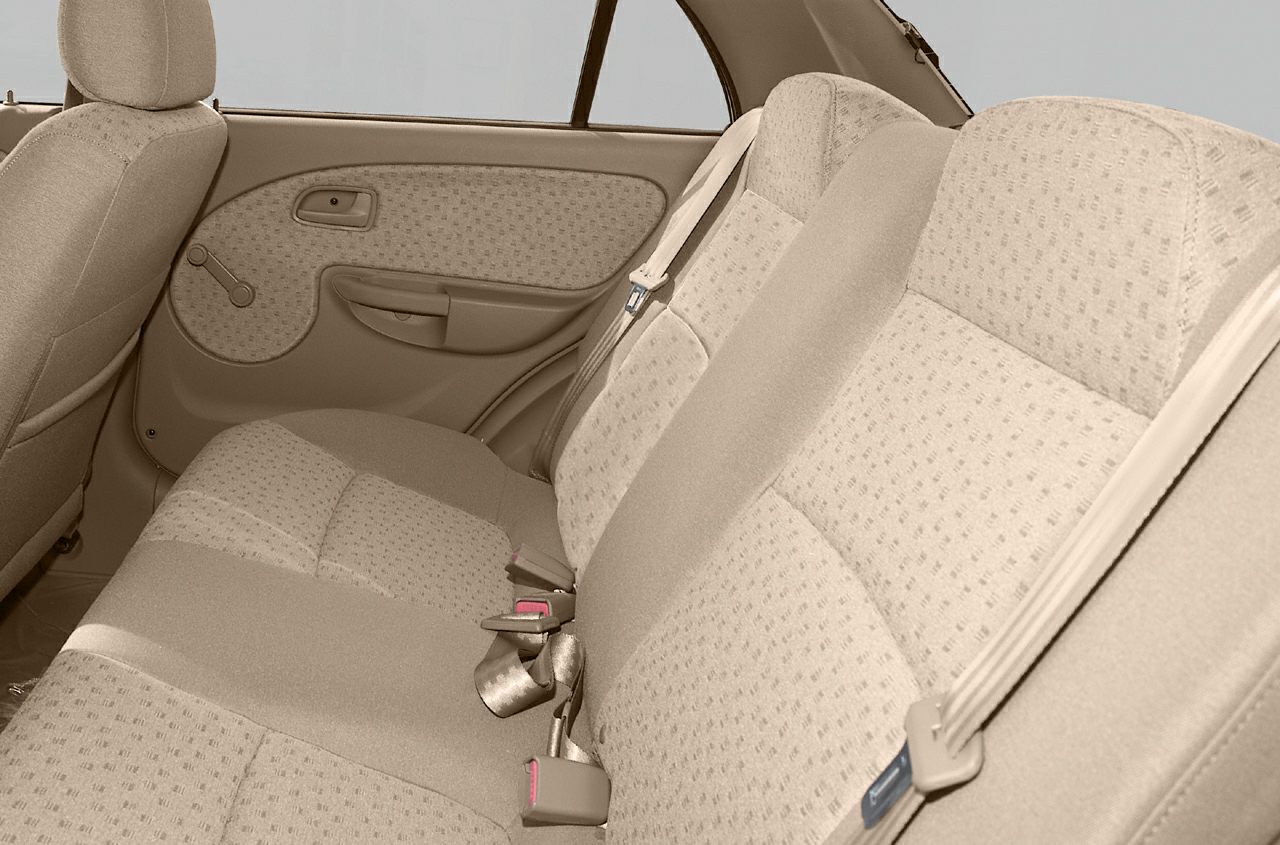 Beige rear seats with fabric upholstery and manual window crank door panel.