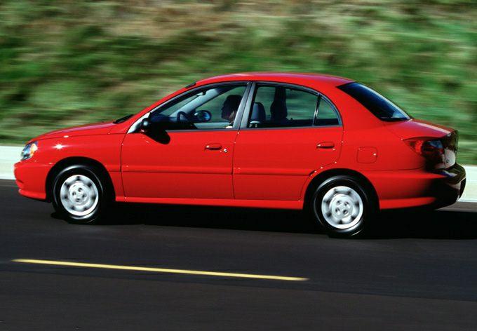 Red compact sedan in side profile with four doors and classic 1999 styling