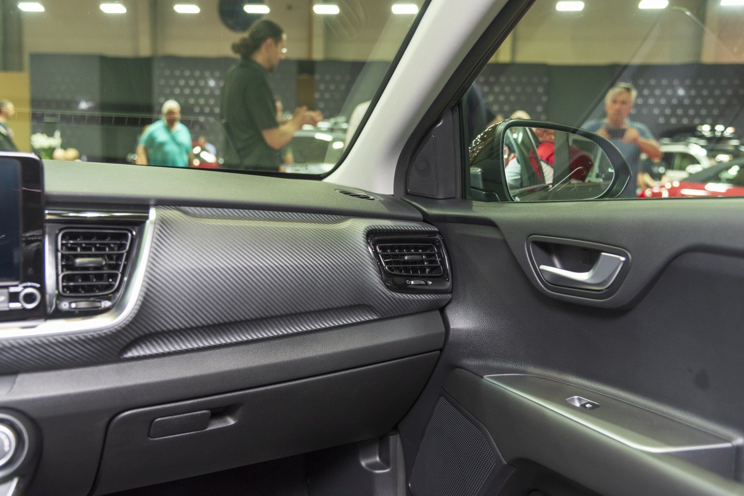 Dashboard corner with carbon fiber texture and door panel with air vent and handle