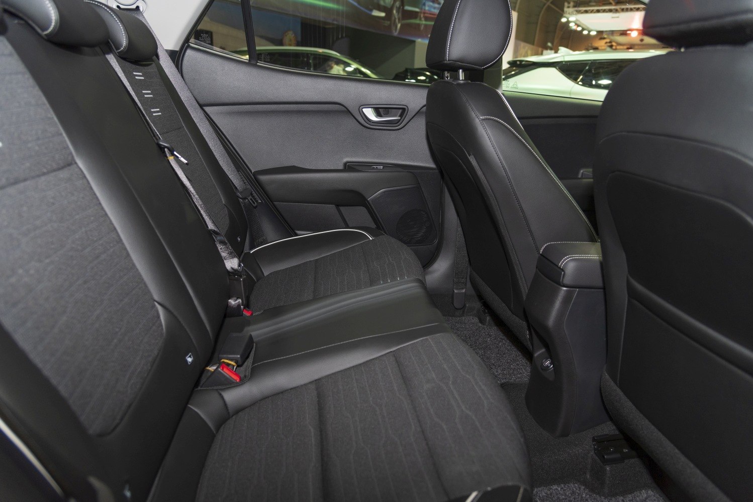 Rear seat interior with black fabric and leather blend upholstery, white stitching.