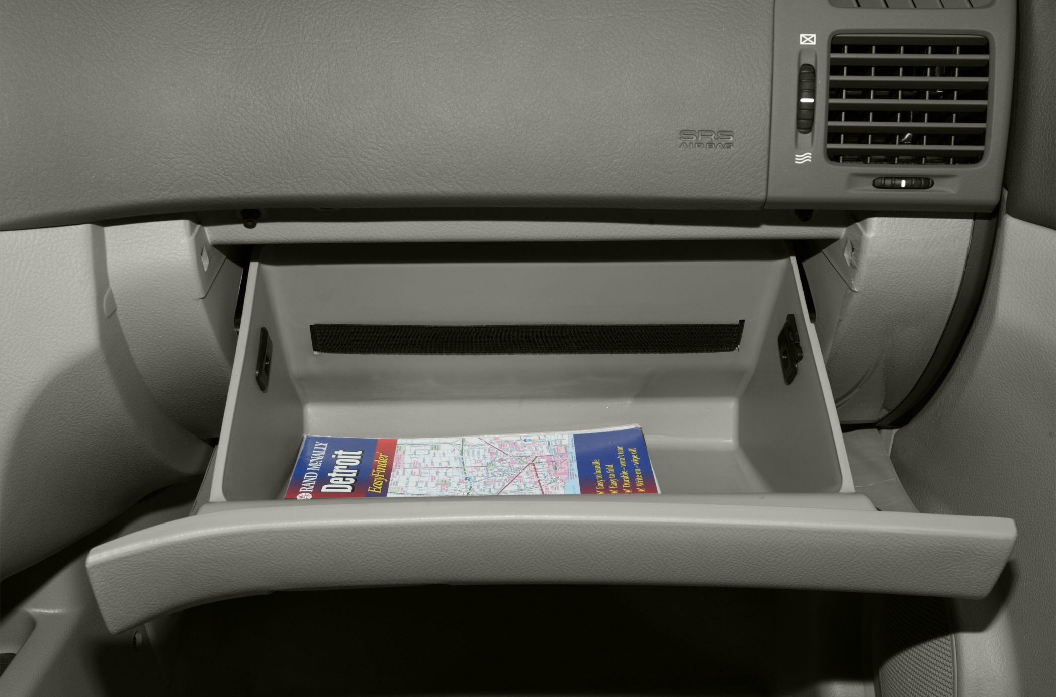 Open glove compartment with a folded map inside on a car dashboard
