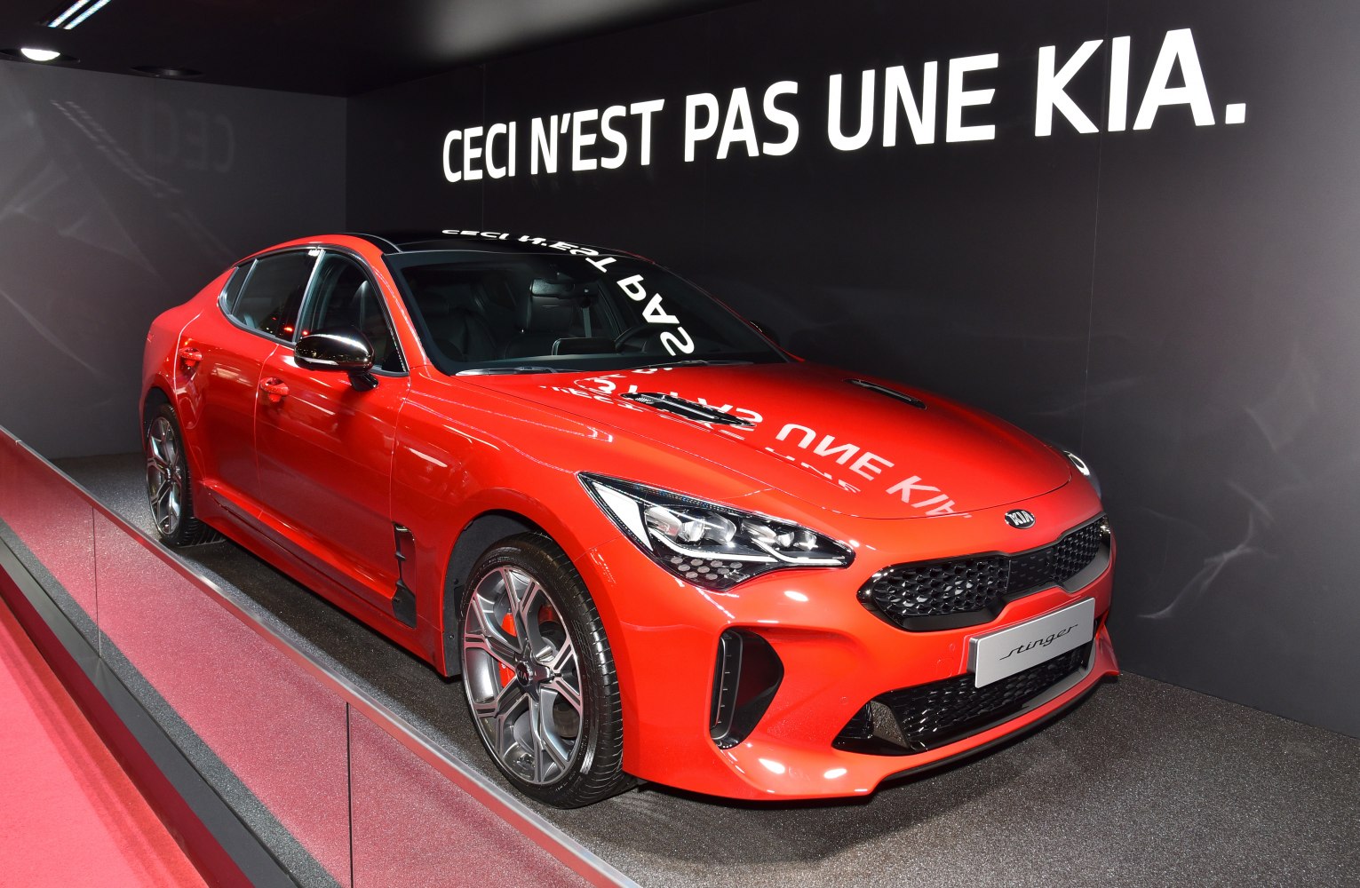 Red sporty front sedan with sleek headlights and hood vents