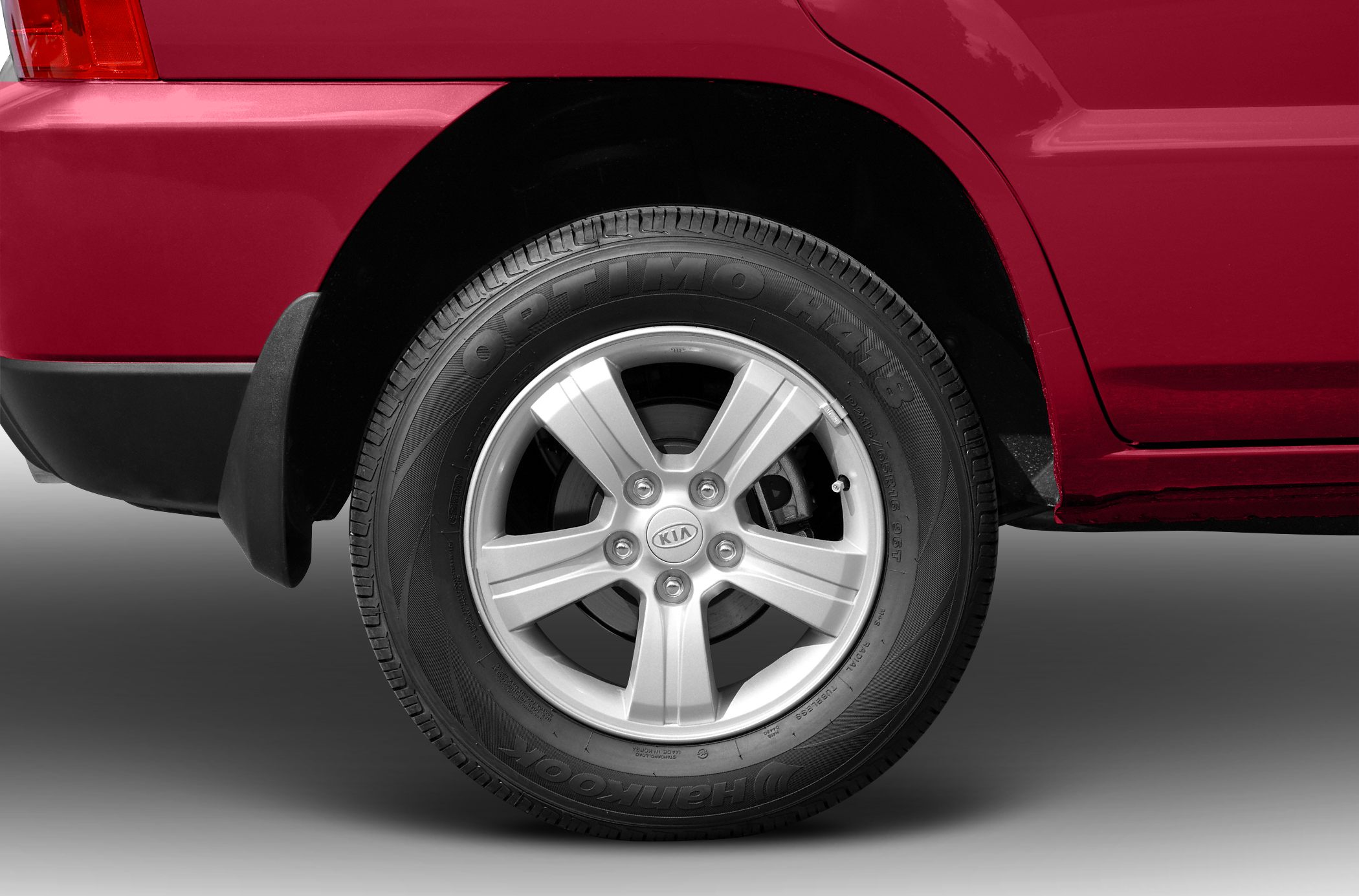 Rear wheel with 5-spoke alloy rim and Hankook Optimo tire on red vehicle.
