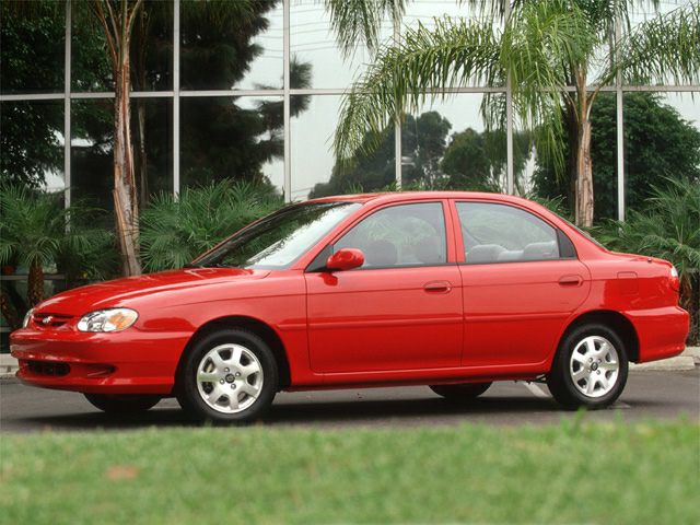 Red four-door sedan with alloy wheels, side profile view