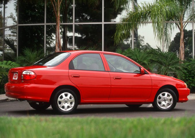 Red compact sedan side view with smooth lines and five-spoke wheels