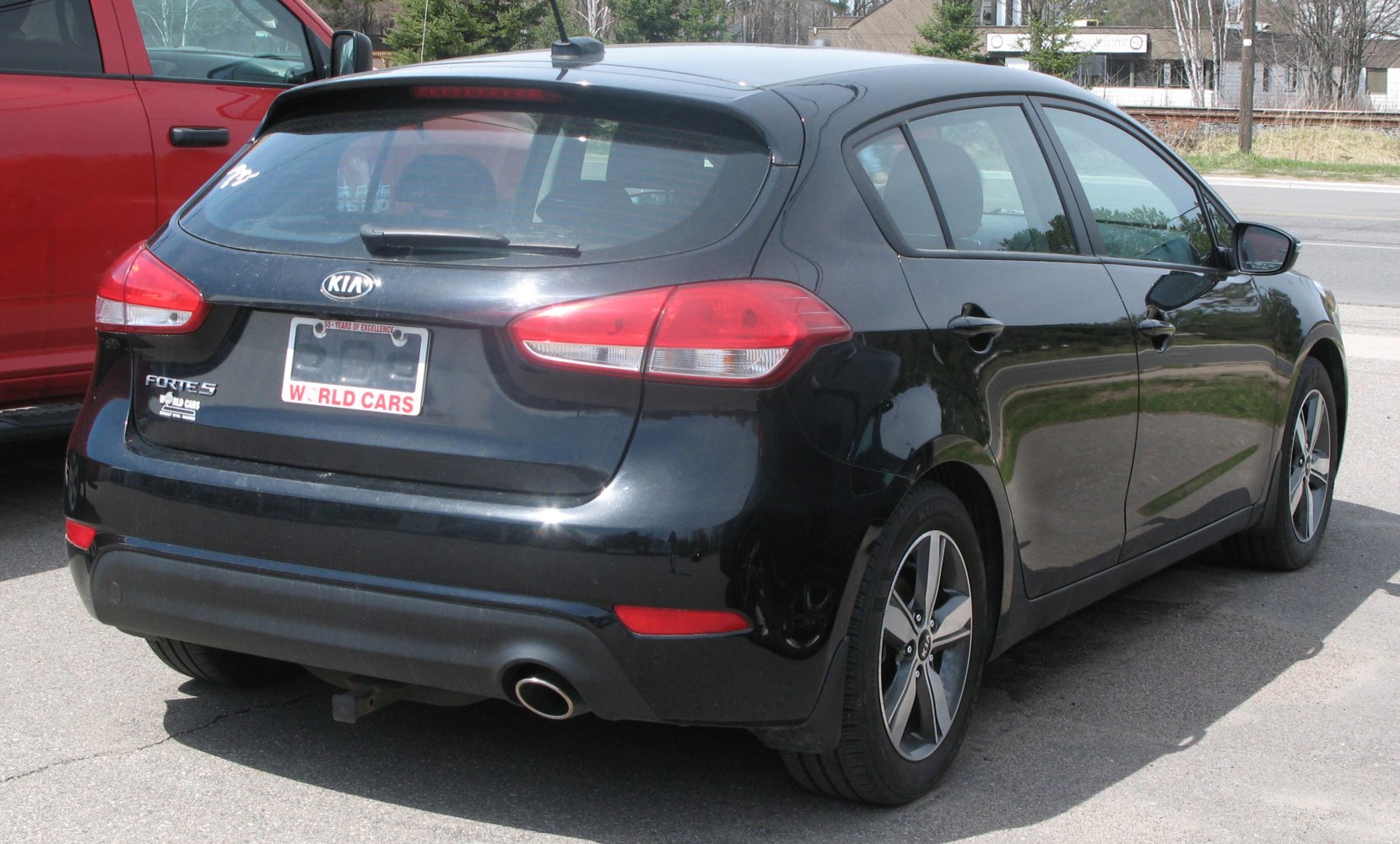 Rear hatchback view with taillights, rear spoiler, exhaust pipe, and alloy wheels