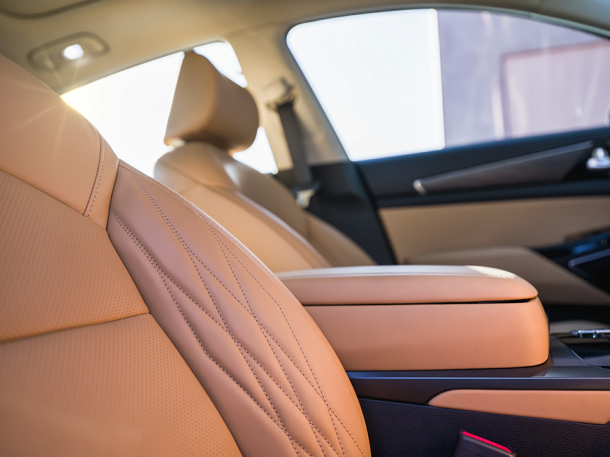 Close-up of tan leather seats and center armrest with detailed stitching