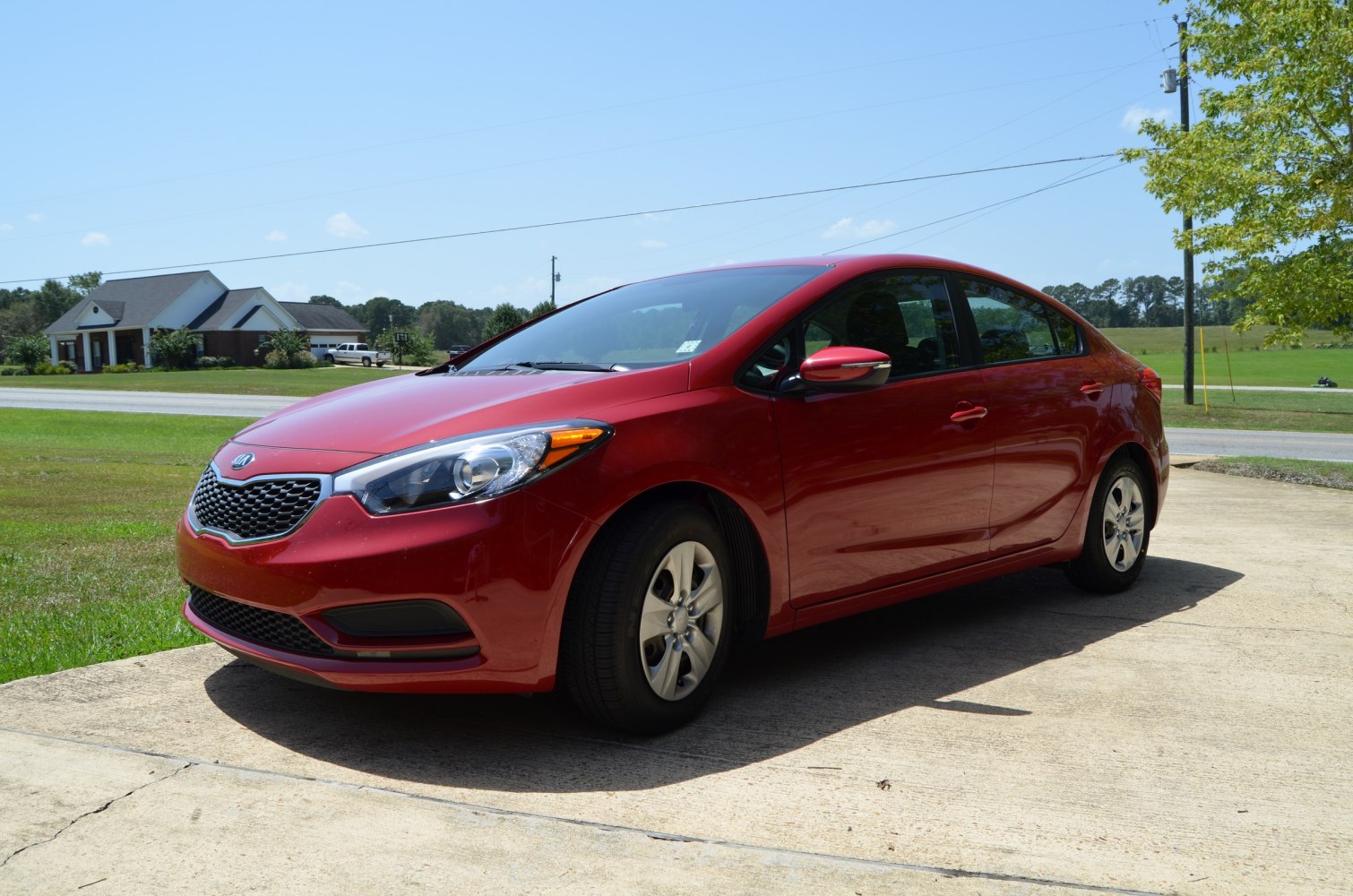 Red compact sedan front and side view on sunny day