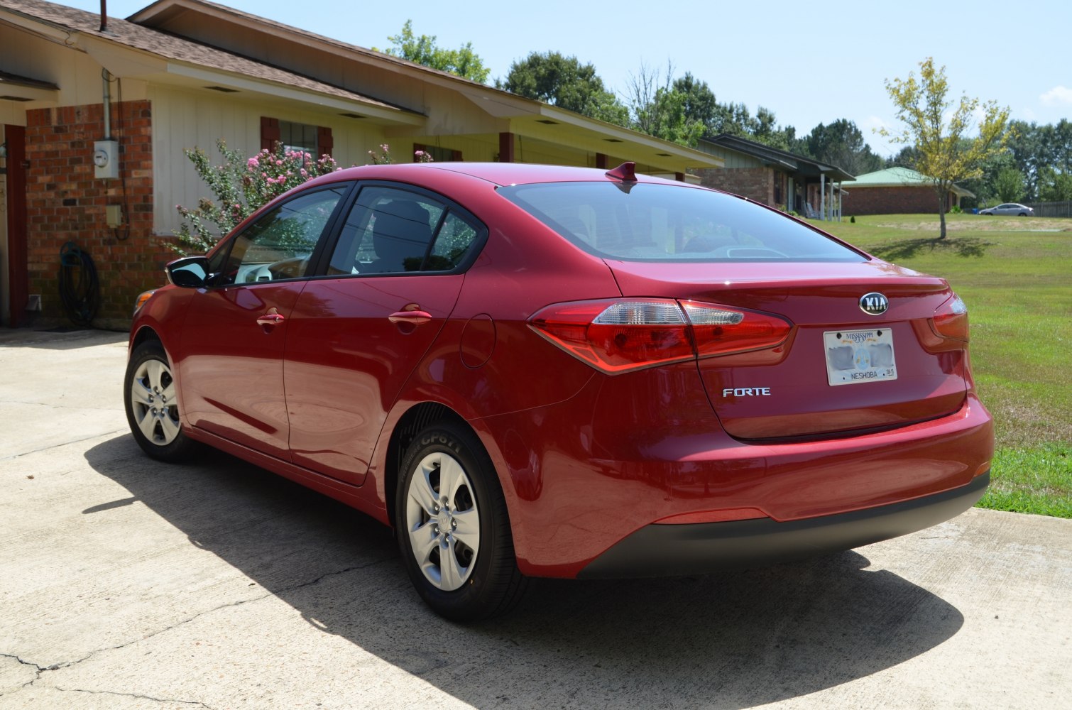 Rear side view of red sedan with tail lights and alloy wheels
