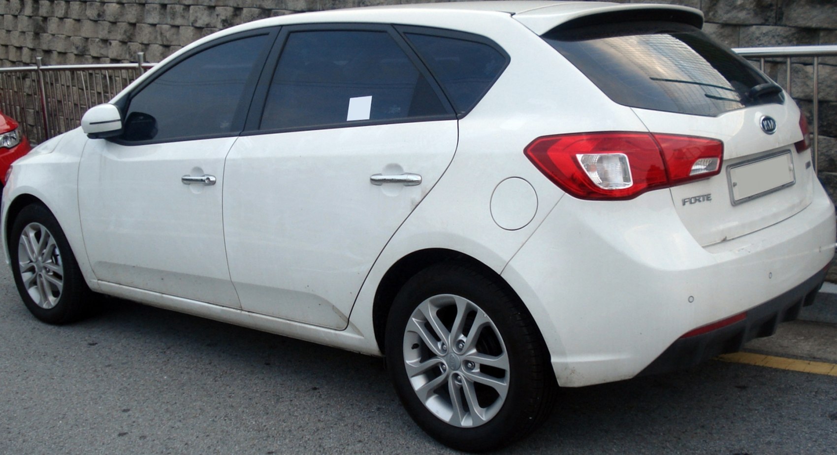 White hatchback rear side with alloy wheels and tinted windows
