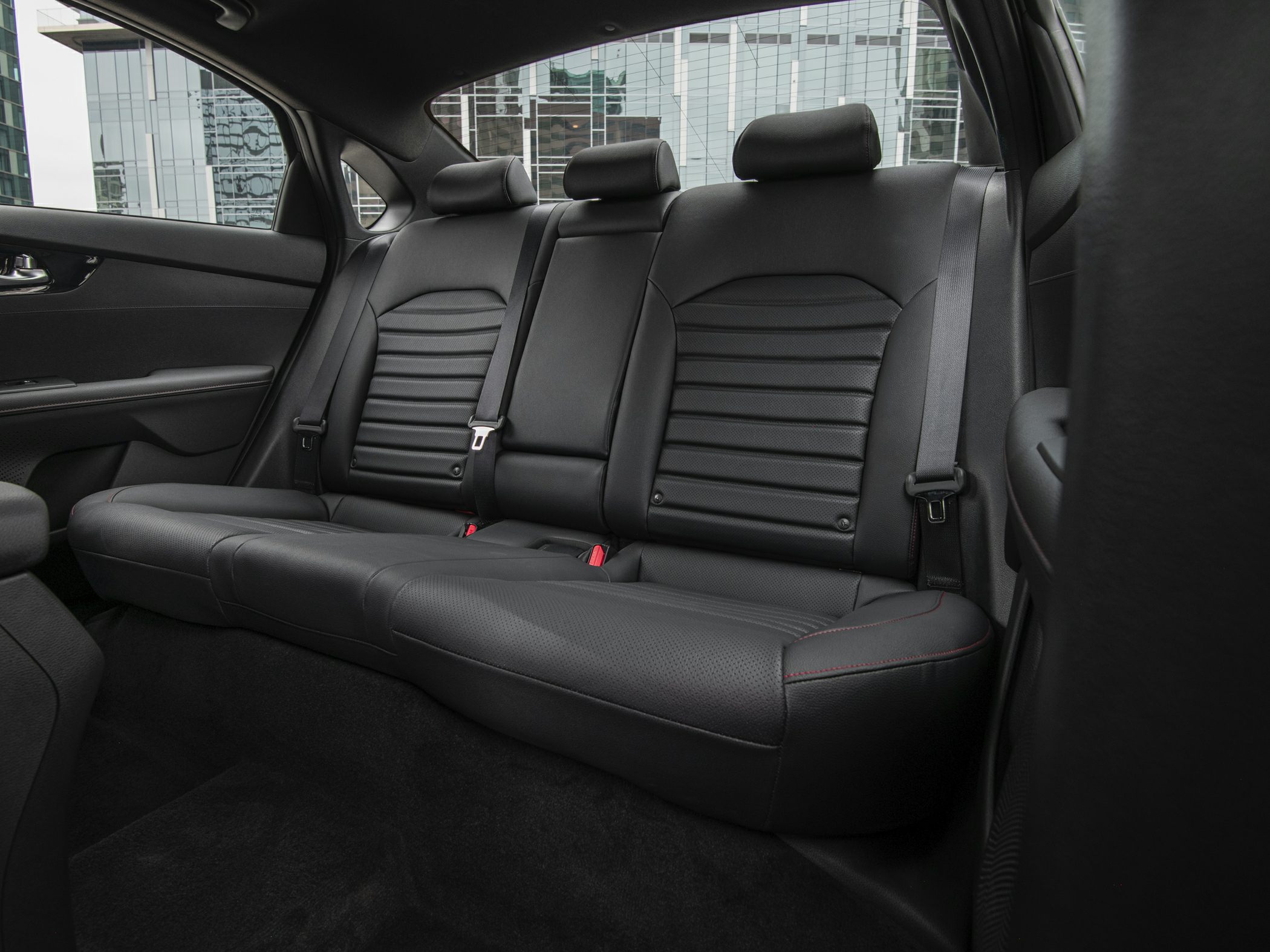 Rear black leather seats with stitching and seat belts in car interior