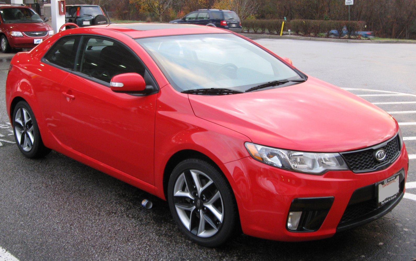 Red compact coupe with sporty alloy wheels and sleek headlights.