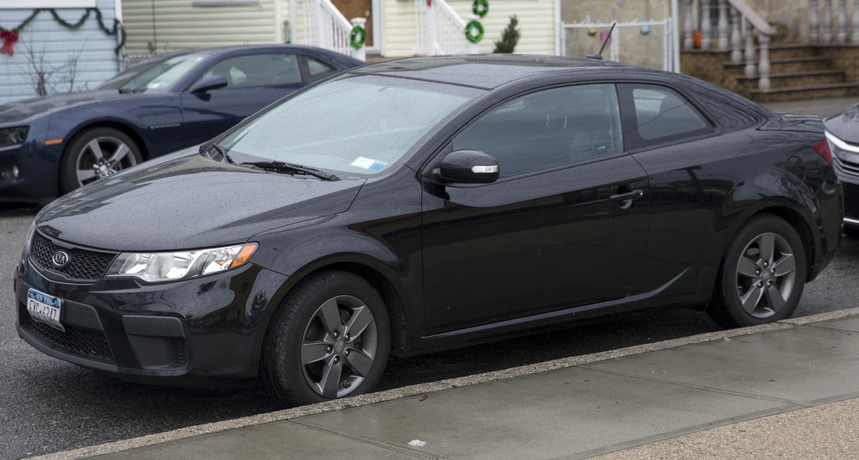 Black coupe with front and side profile, alloy wheels, rainy street parking