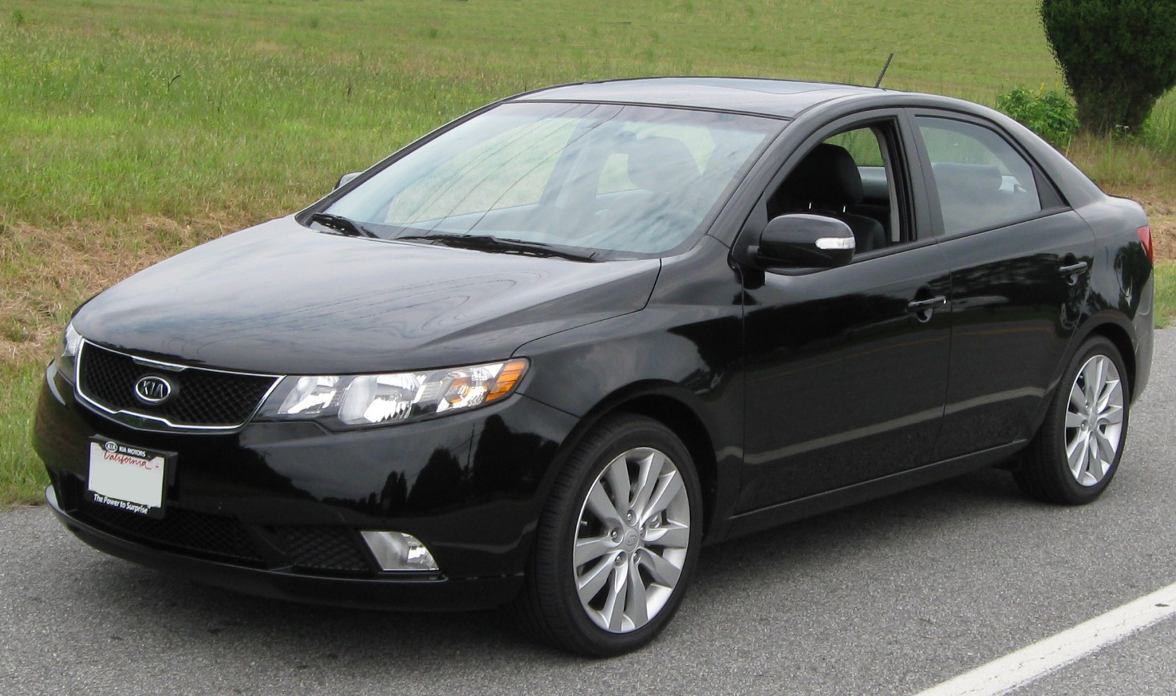 Black compact sedan front-side view with alloy wheels