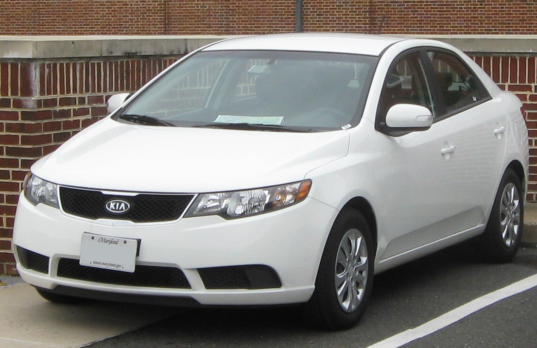 White compact sedan showing front three-quarter view including headlights and side mirrors.