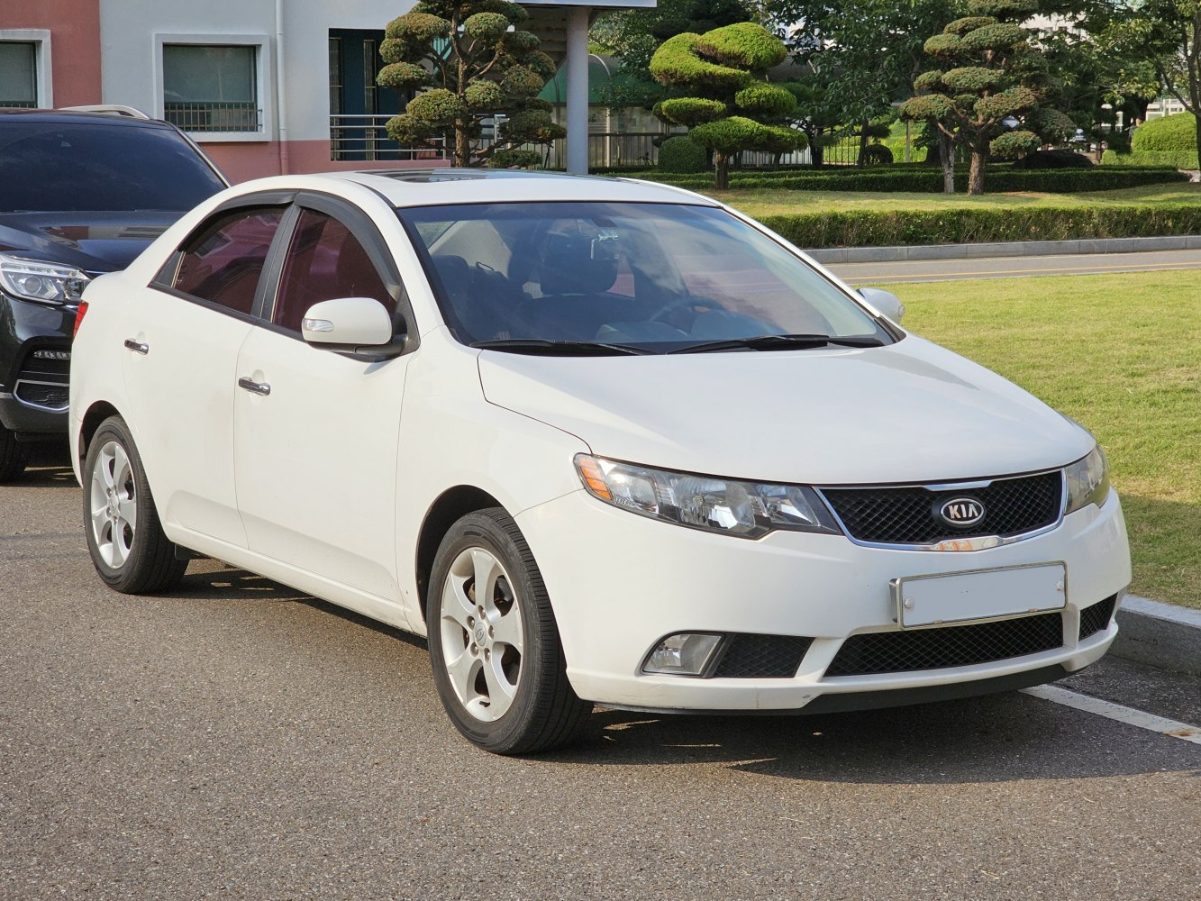 White sedan with front 3-4 view, headlights, grille, and alloy wheels