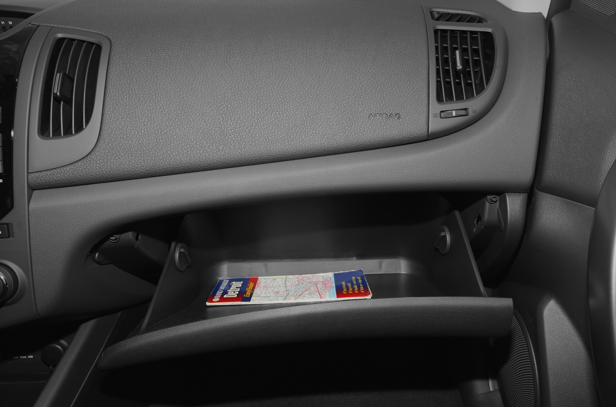 Open glove compartment with map inside on textured dashboard panel