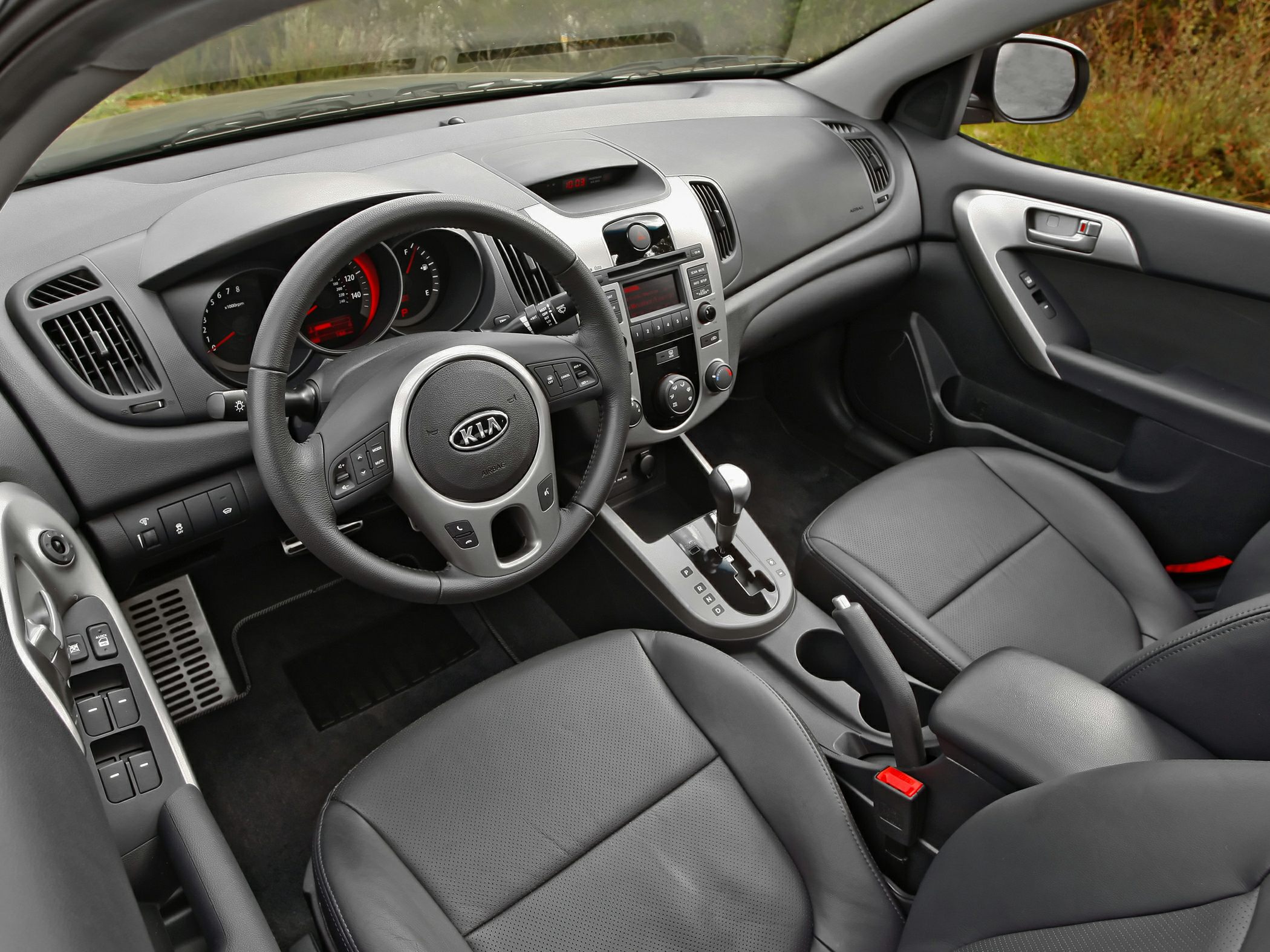 Steering wheel, dashboard, center console, and black leather seats.