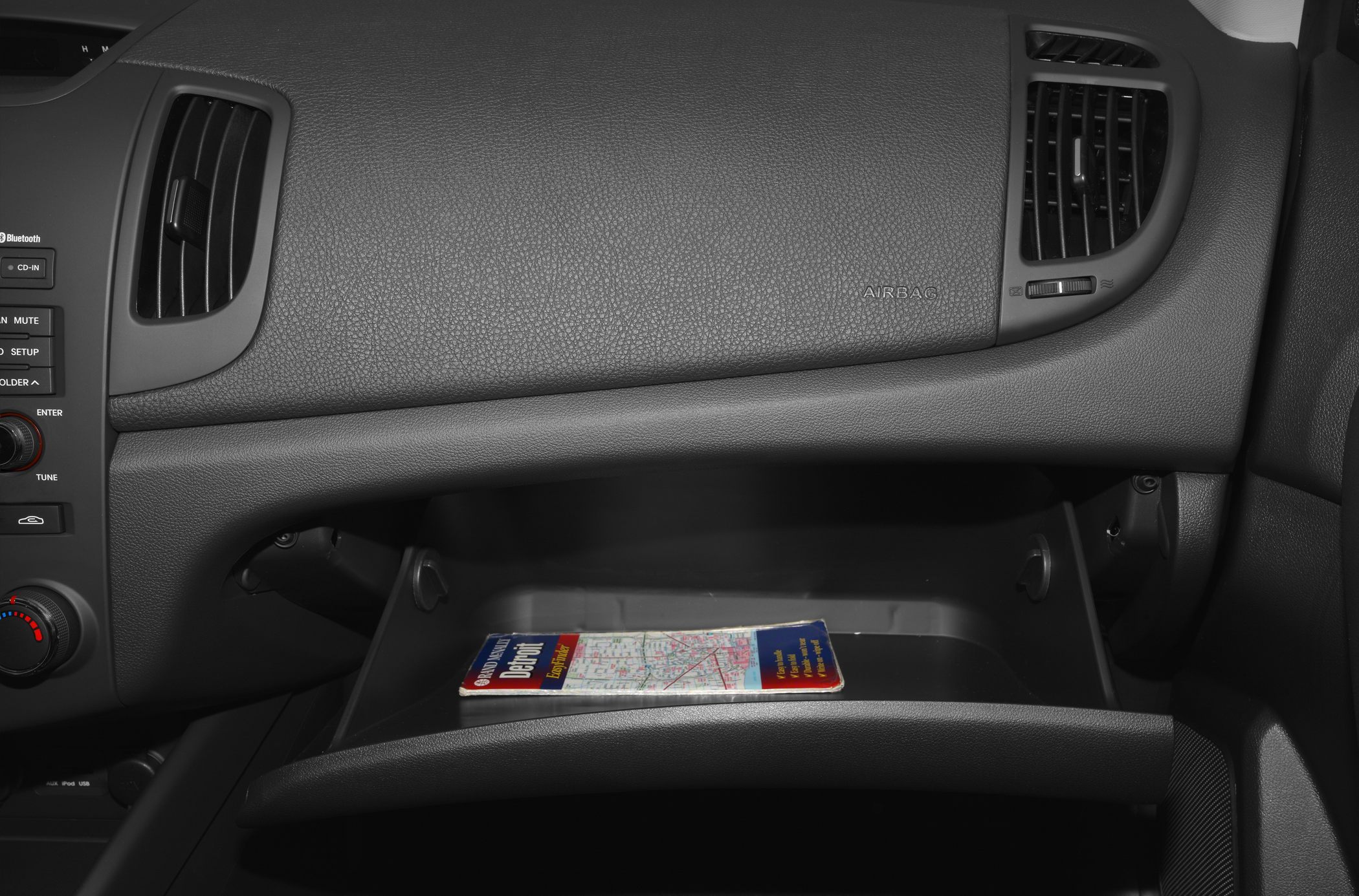 Open glove compartment with textured dashboard and ventilation vents.