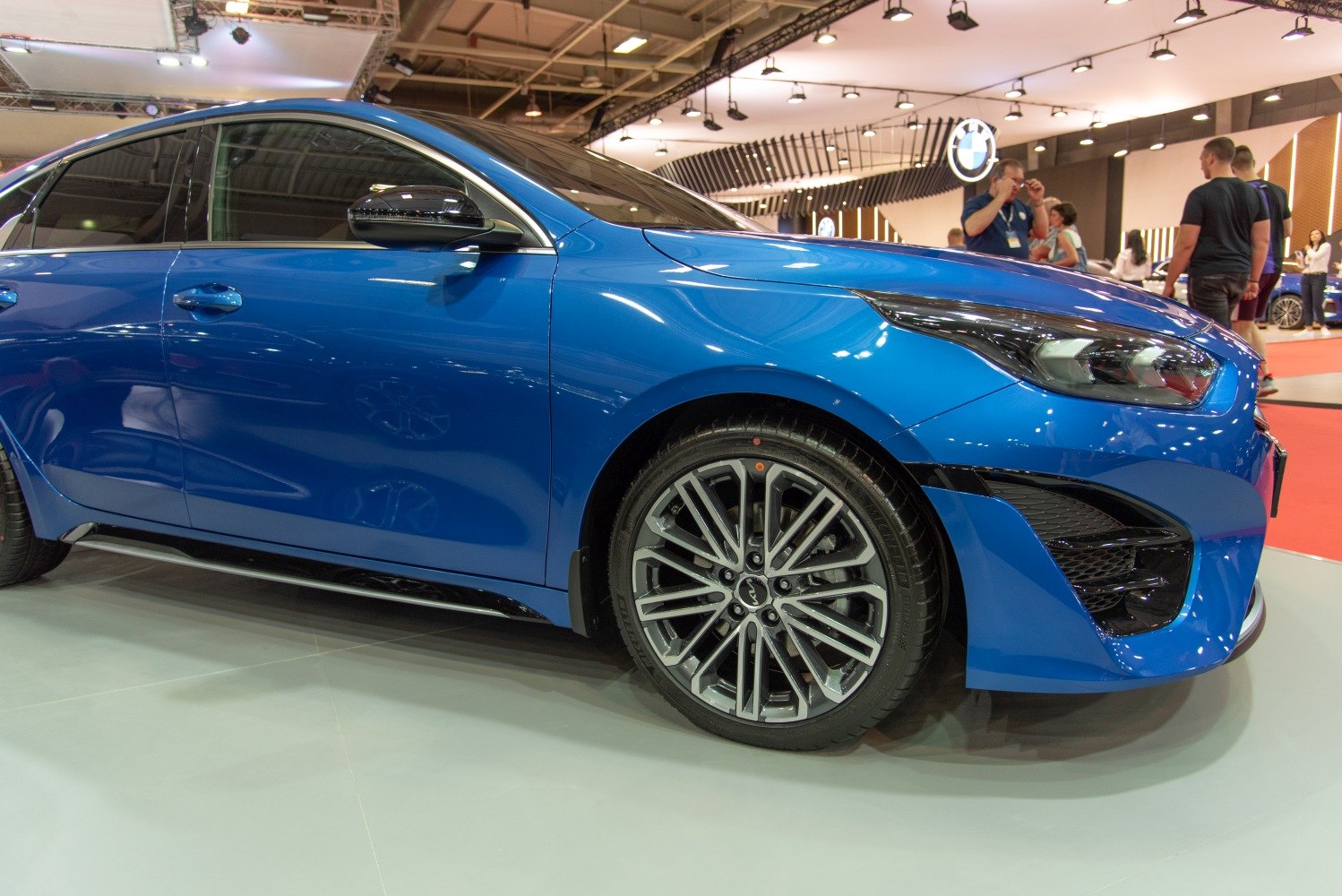 Close-up of alloy wheels and sleek headlight on blue hatchback side