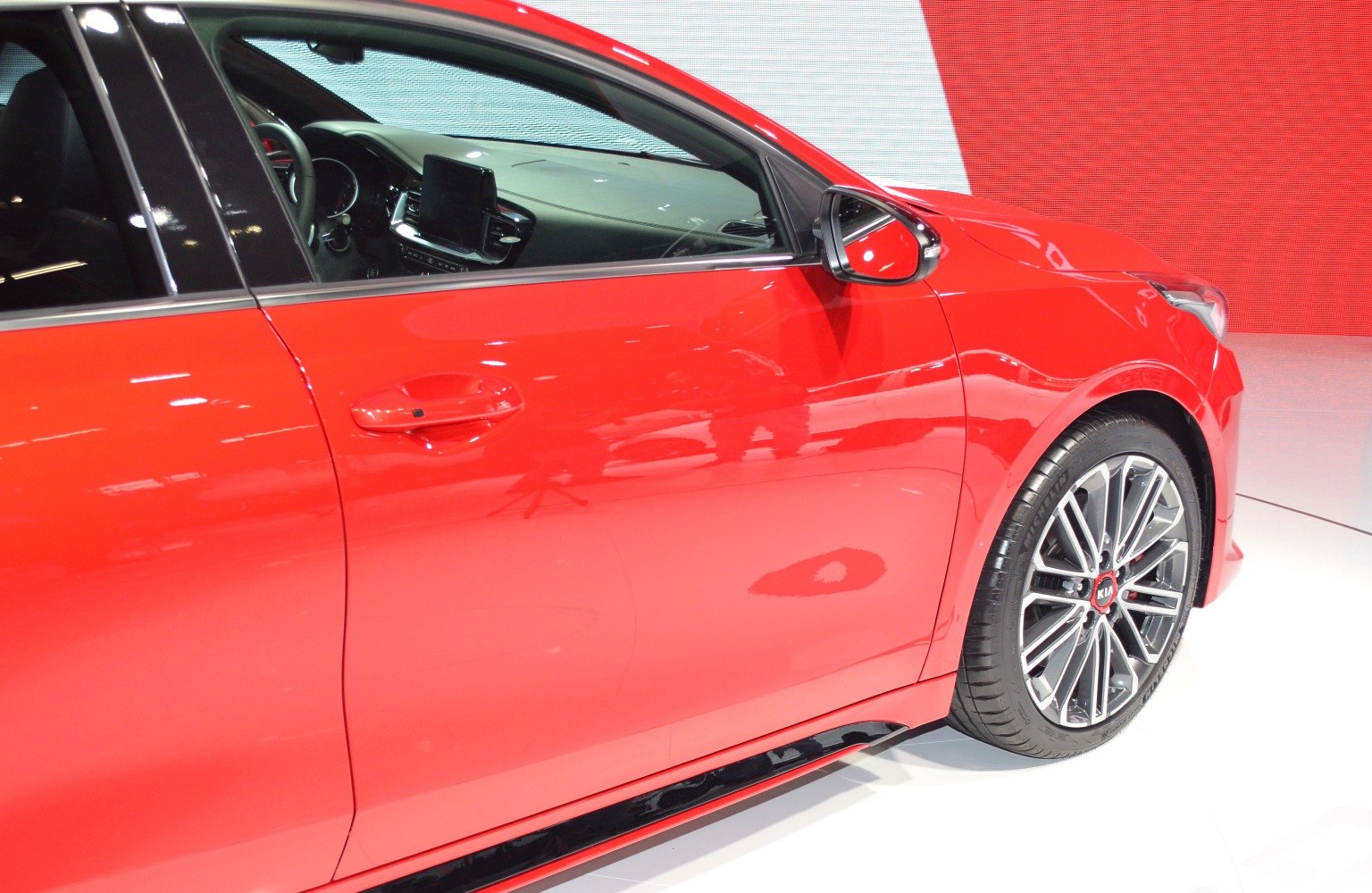 Red car side door with distinctive alloy wheel and interior display