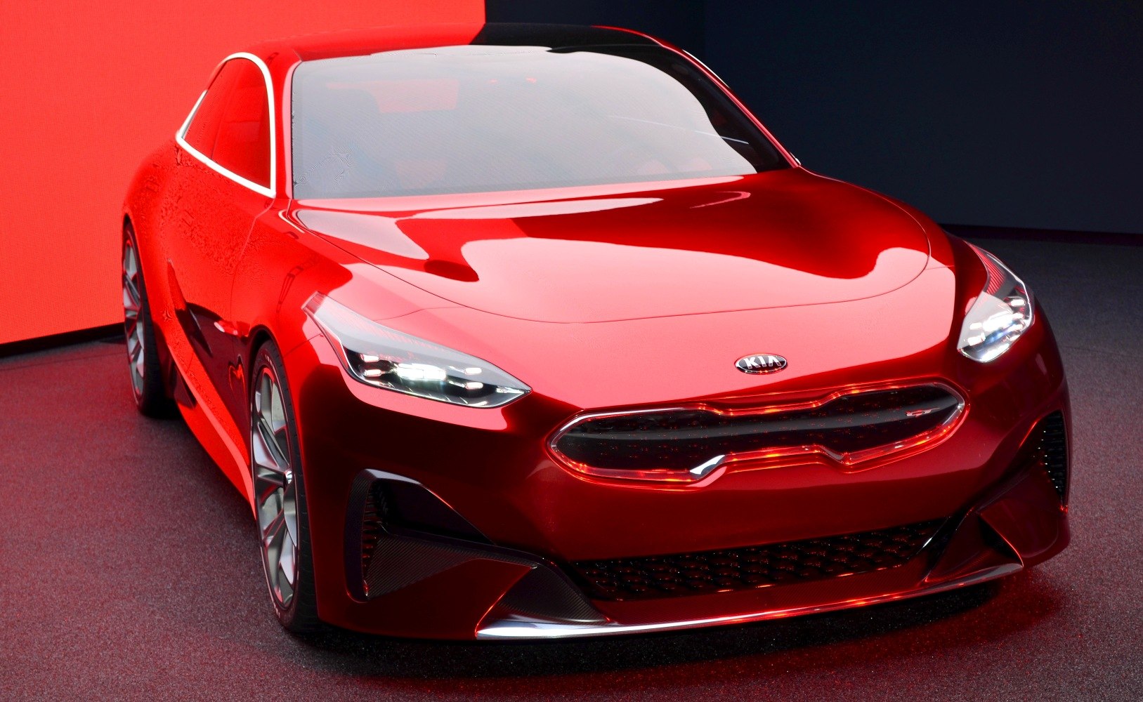 Glossy red modern car with sharp LED headlights and bold front grille