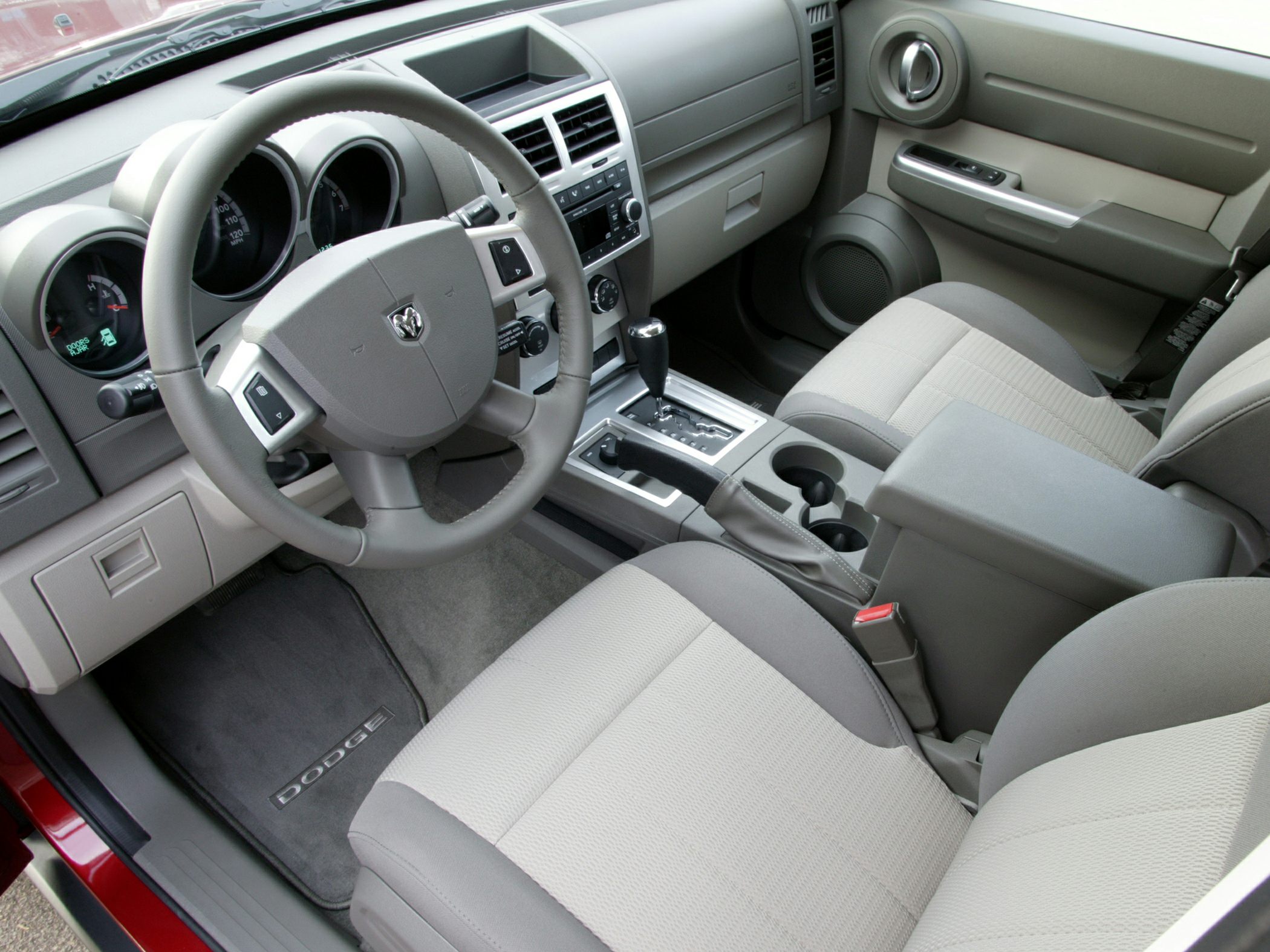 Interior view of dashboard, steering wheel, and front seats in neutral tones.