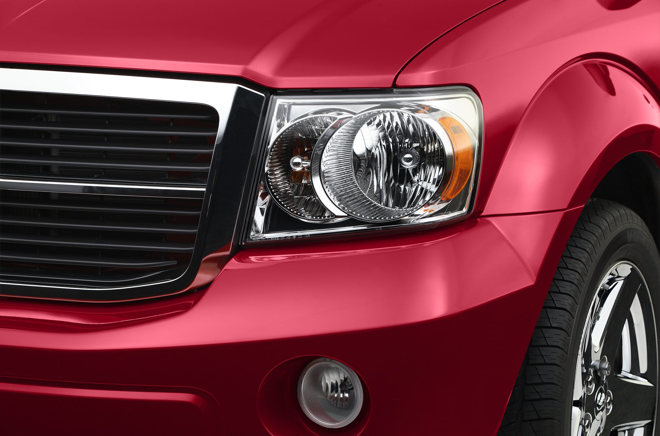 Close-up of front headlight, grille, and fender with chrome wheel